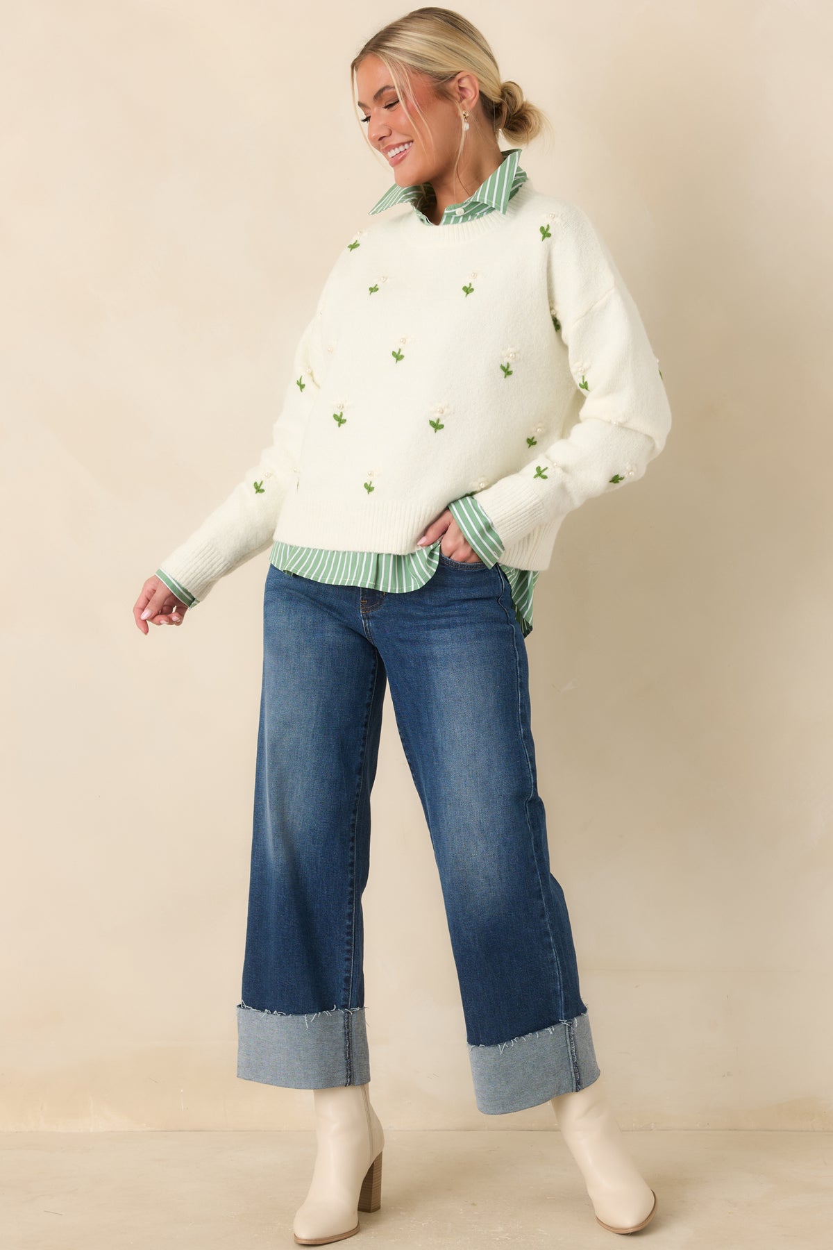 Model wearing dark wash wide-leg stretch jeans with oversized turned cuffs, paired with brown heeled ankle boots