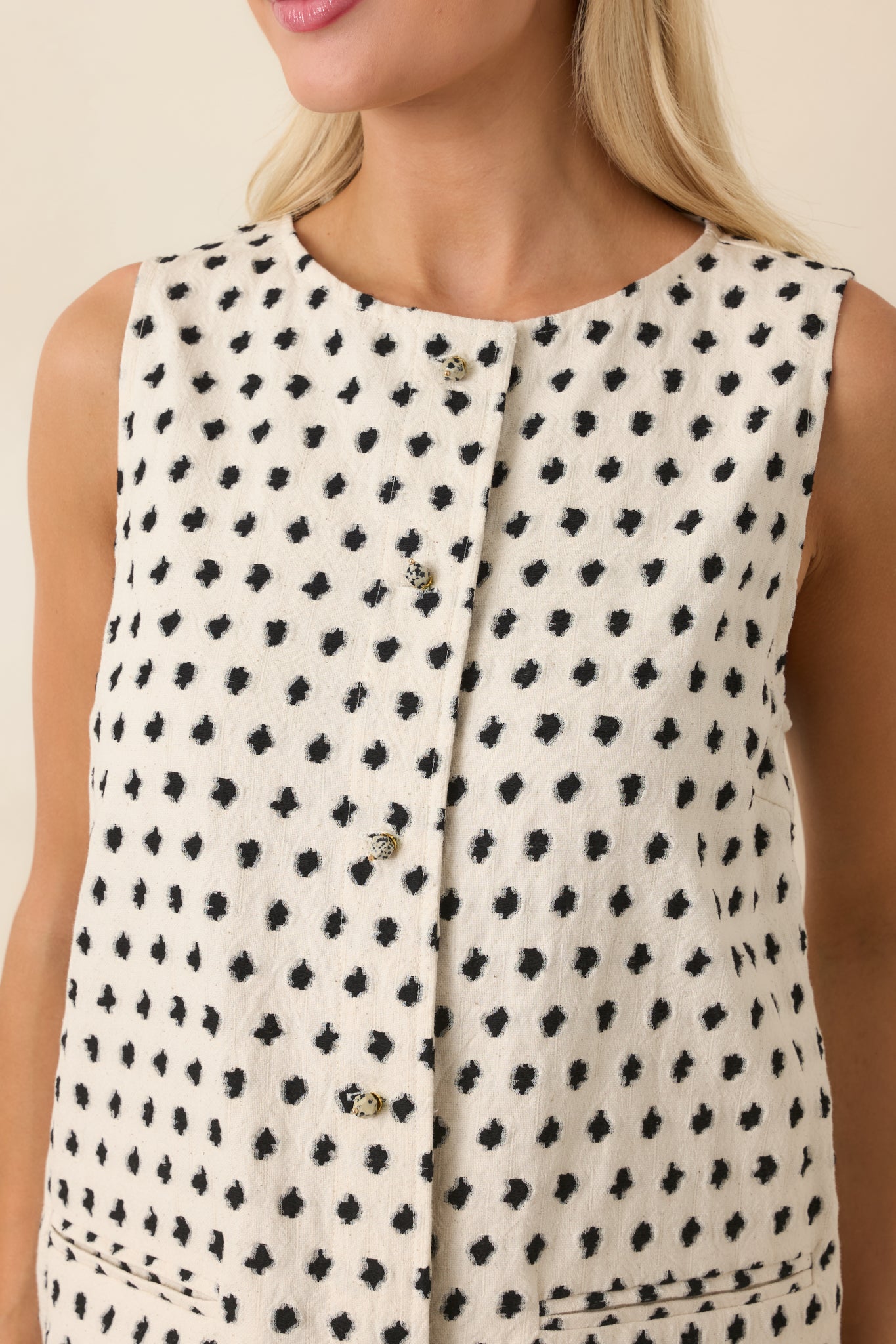 Decorative bead-style buttons and abstract black dot pattern on ivory fabric.