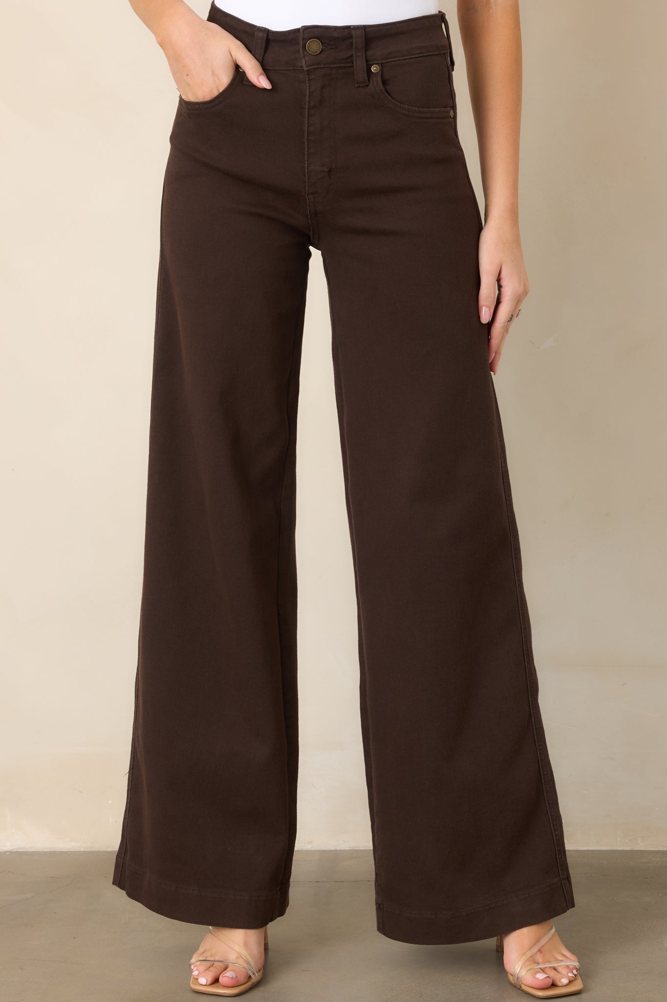 Close view of the deep brown denim highlighting the high-rise waistband, belt loops, and clean wide-leg construction.