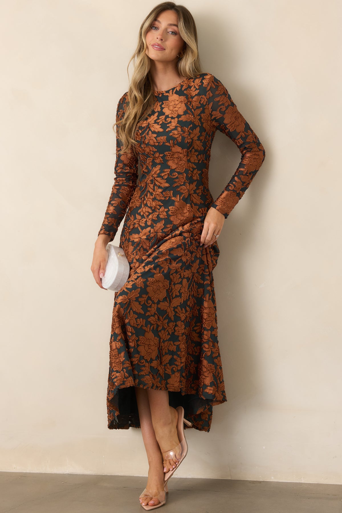 Deep green midi dress with raised copper floral motifs, a fitted bodice, long sleeves, and a flowing skirt.