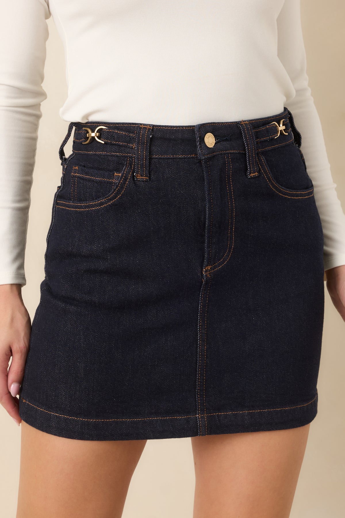 Deep indigo skirt featuring warm contrast stitching along the pockets and gently flared hem.