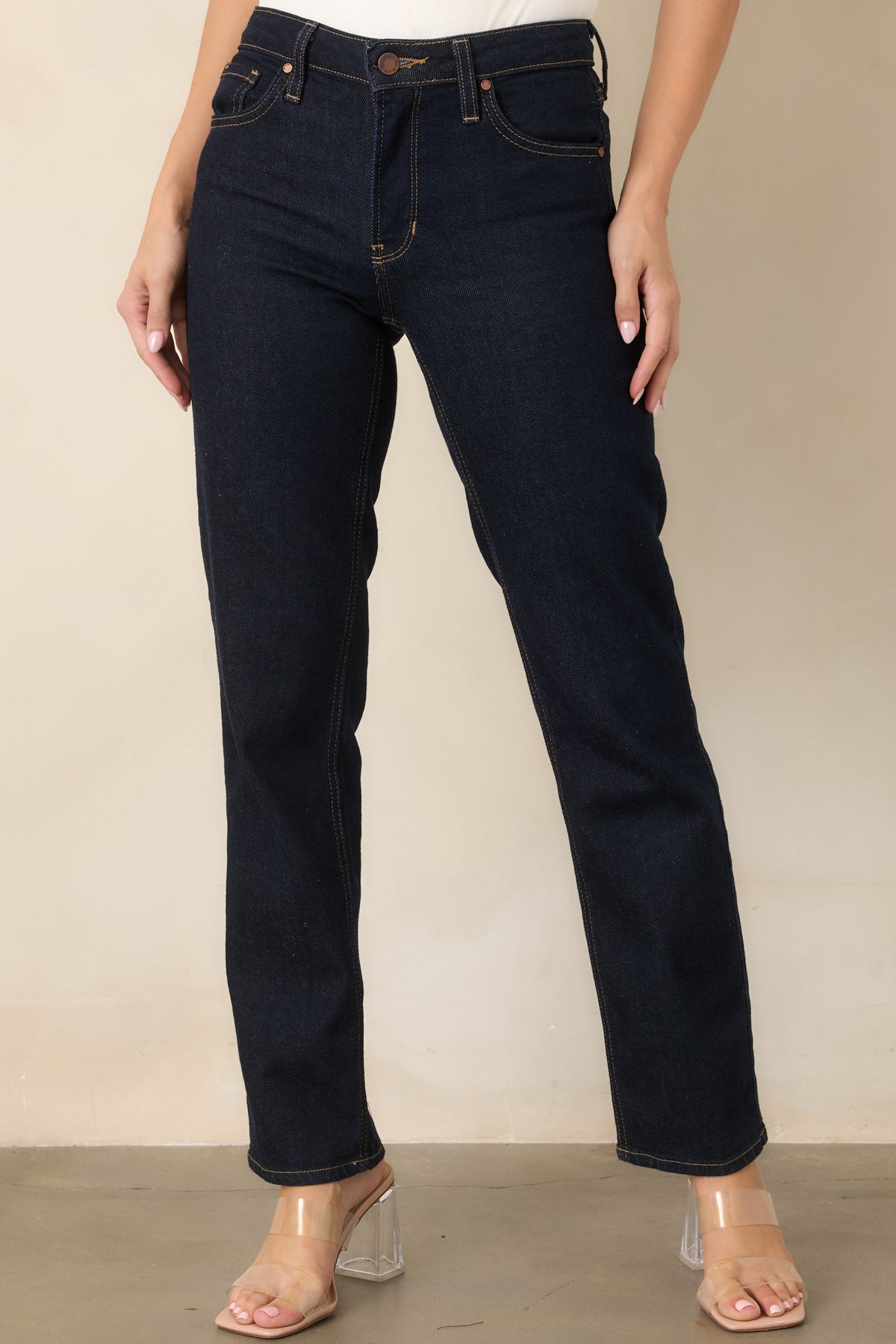 Deep indigo jeans highlighting the high-rise waistband, belt loops, and classic button-and-zip front closure.