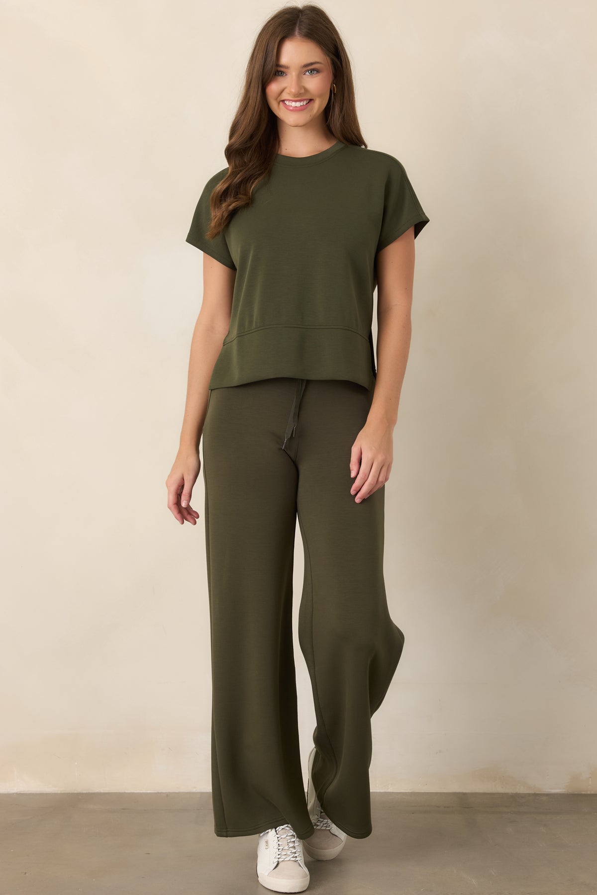 Deep olive-green top featuring a classic crew neckline, short sleeves, and an elevated high-low hem with side slits.