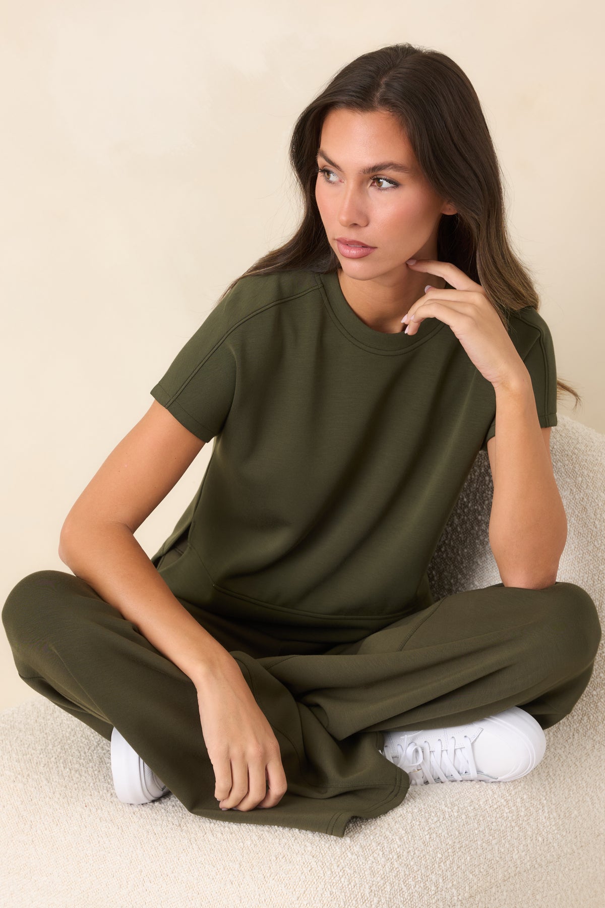 Deep olive-green top with a classic crew neckline, short sleeves, and elevated high-low hem.