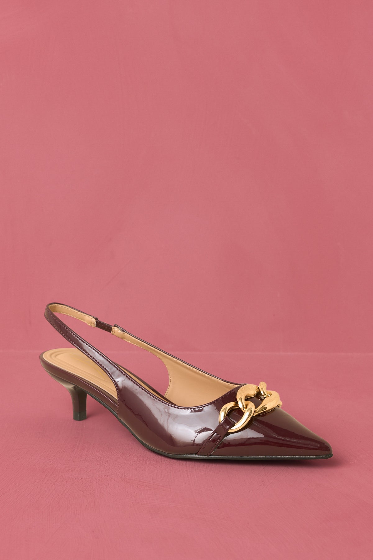 Deep plum patent slingback heels against a rose backdrop.
