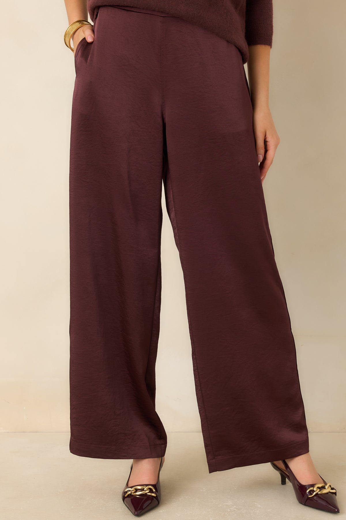Smooth front waistband on the deep wine pants creates a clean finish above the softly textured fabric.