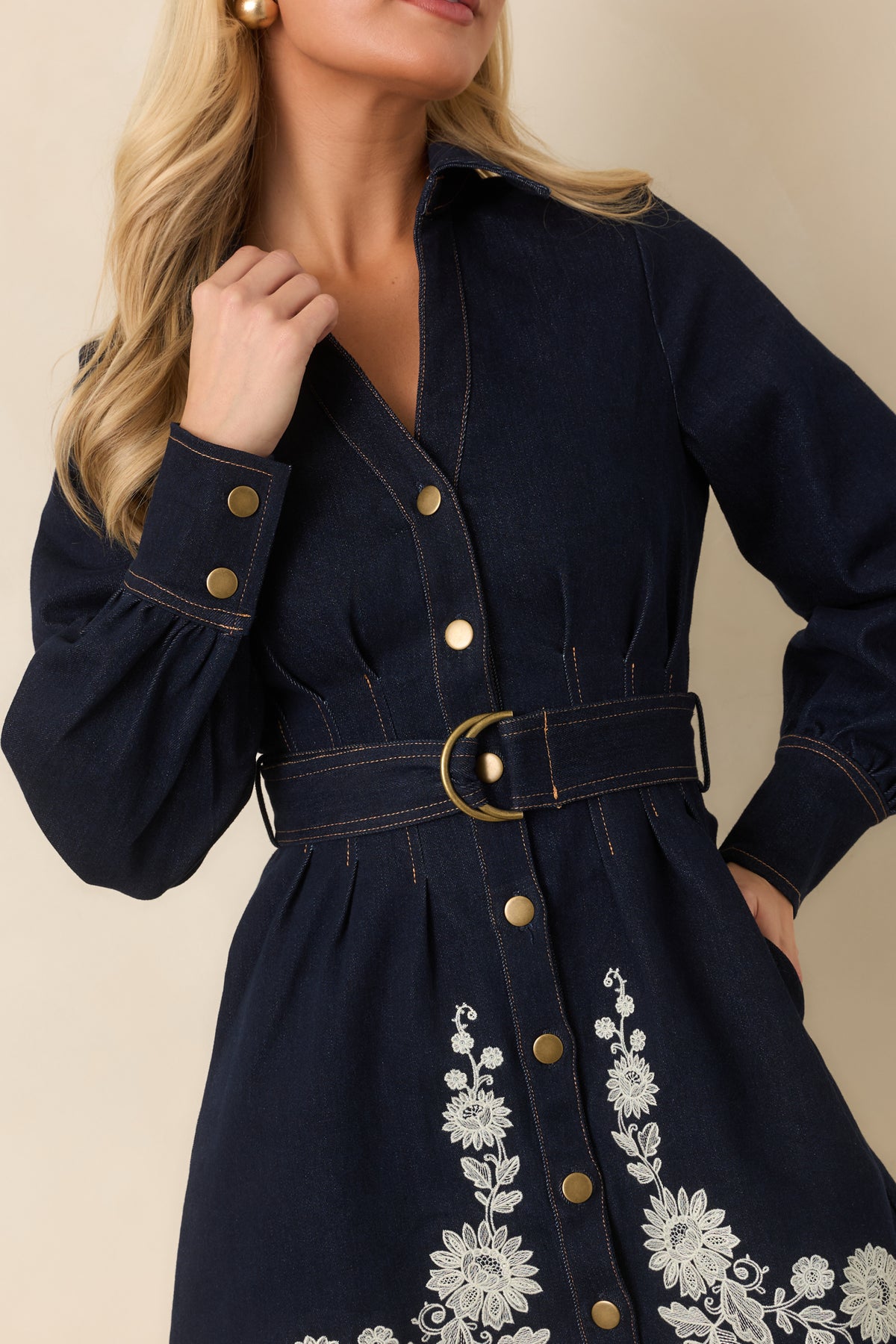 Indigo denim dress highlighting the gold-tone buttons and matching belt hardware at the defined waist.