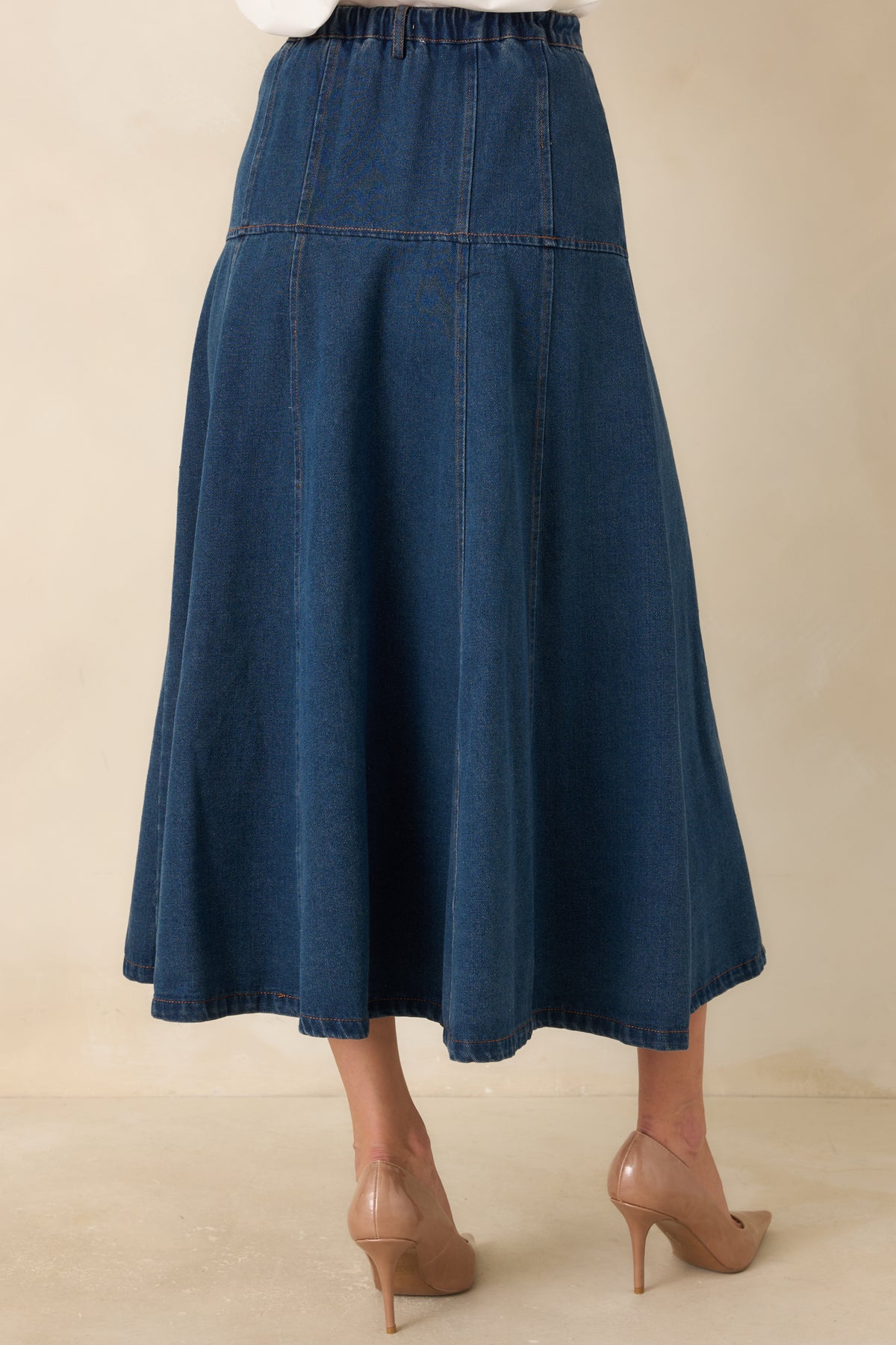 Rear view of the denim midi skirt showing the elasticized back waistband and flared A-line shape.