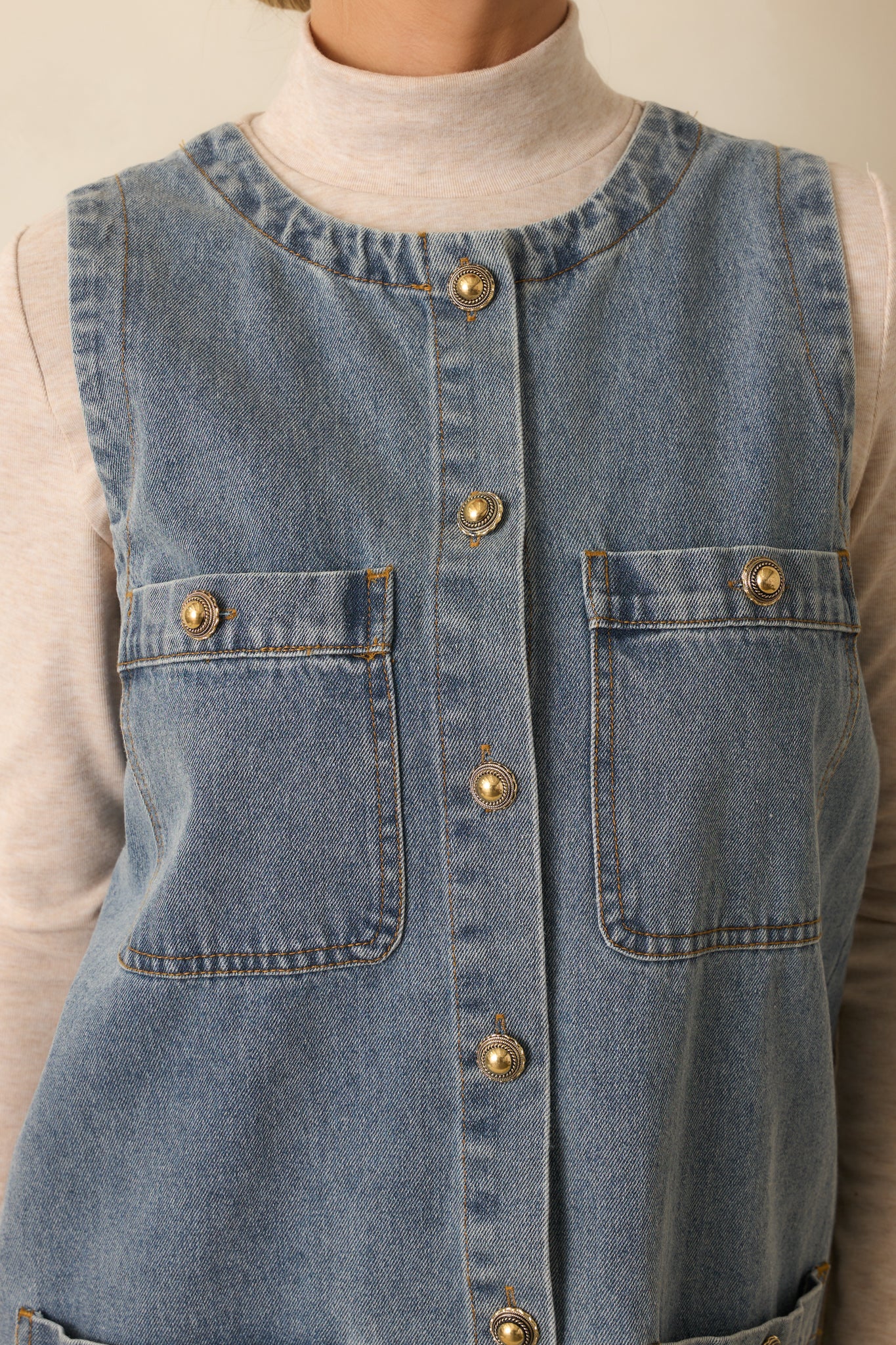 A detailed close-up of the dress showing the button front, pocket edges, and medium-wash denim texture.