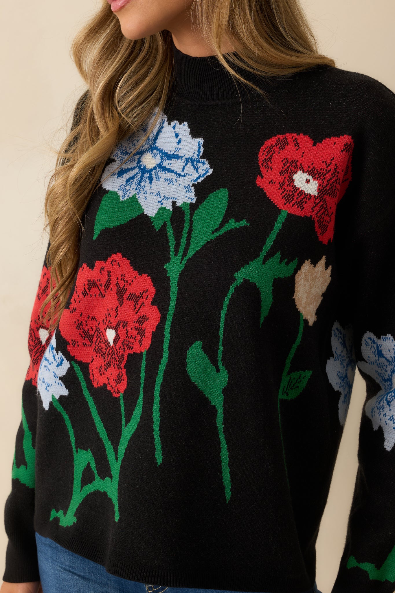 Detailed shot of the black sweater showcasing the multicolor floral jacquard, ribbed neckline, and soft knit texture.