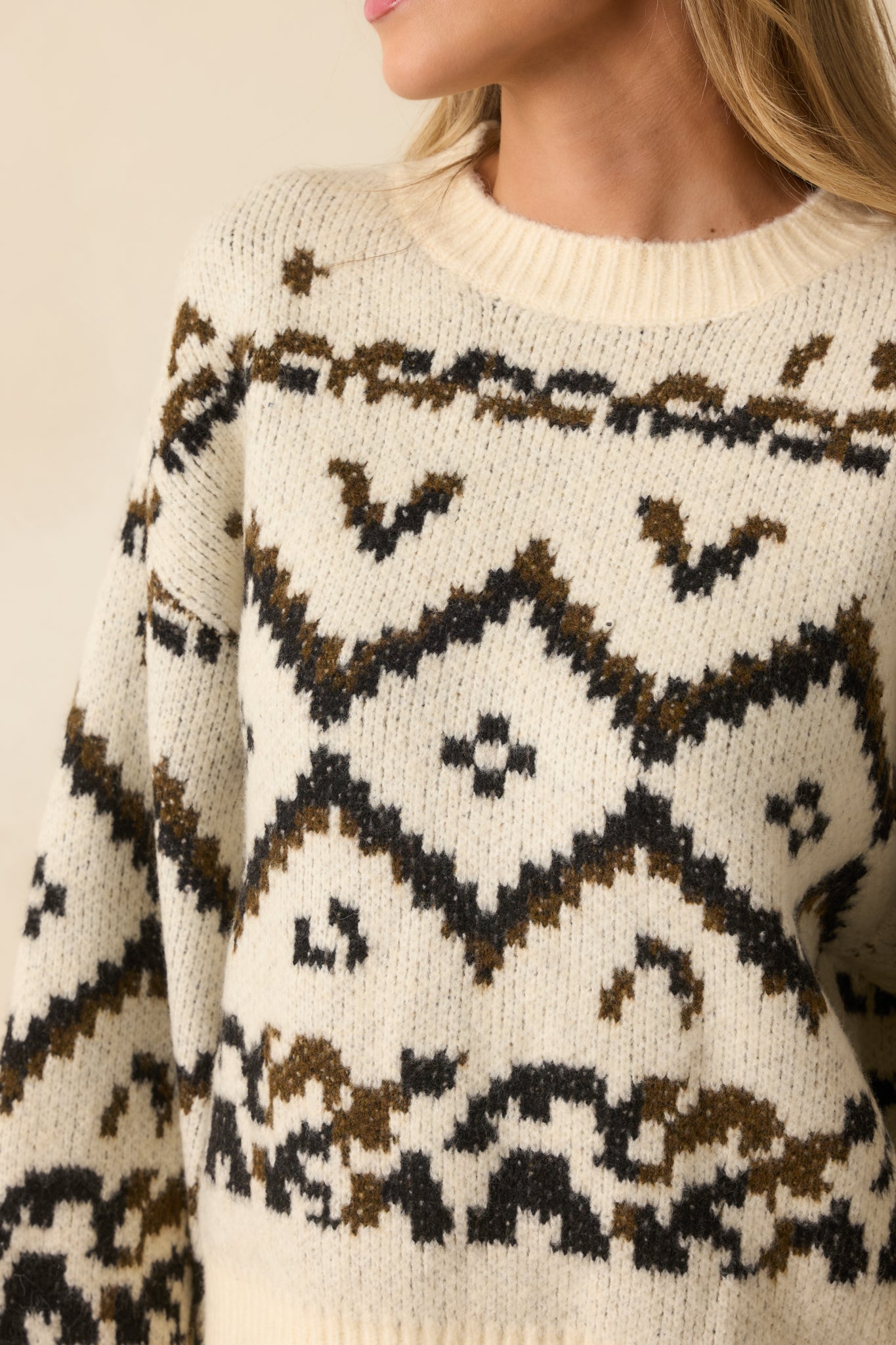 Detailed view of the multicolor brown Fair Isle–inspired knit against the ivory sweater fabric.
