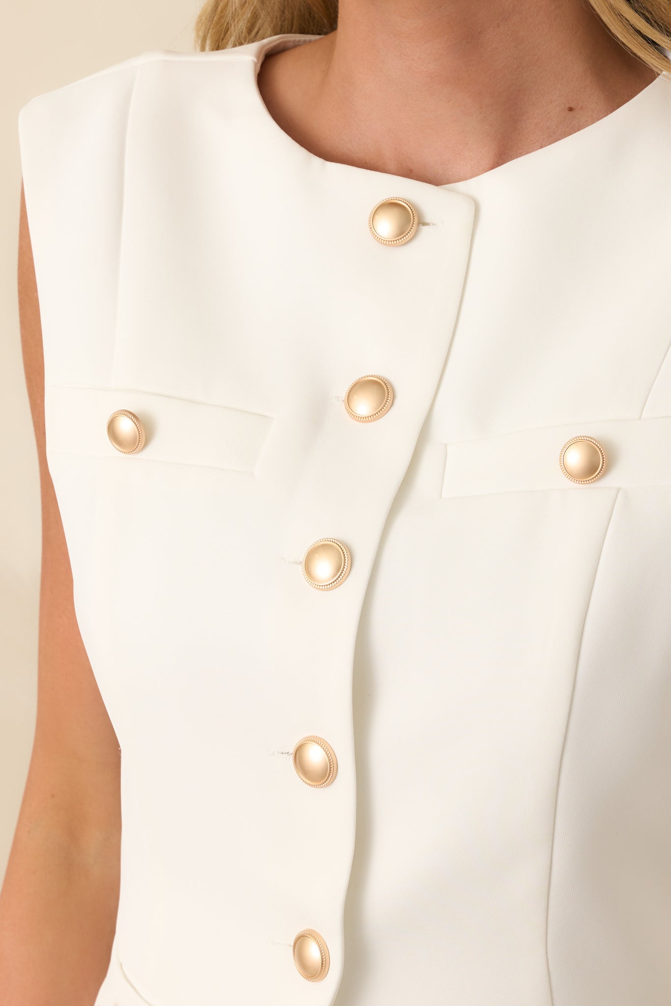 Close-up detail of a functional button and pocket flap on the white top.