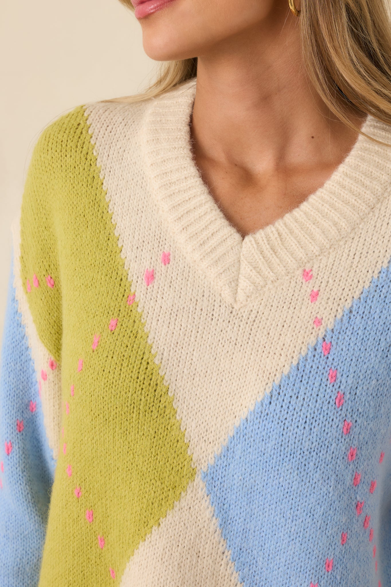 Zoomed detail of green and blue argyle knit pattern showing soft yarn and diamond stitching.