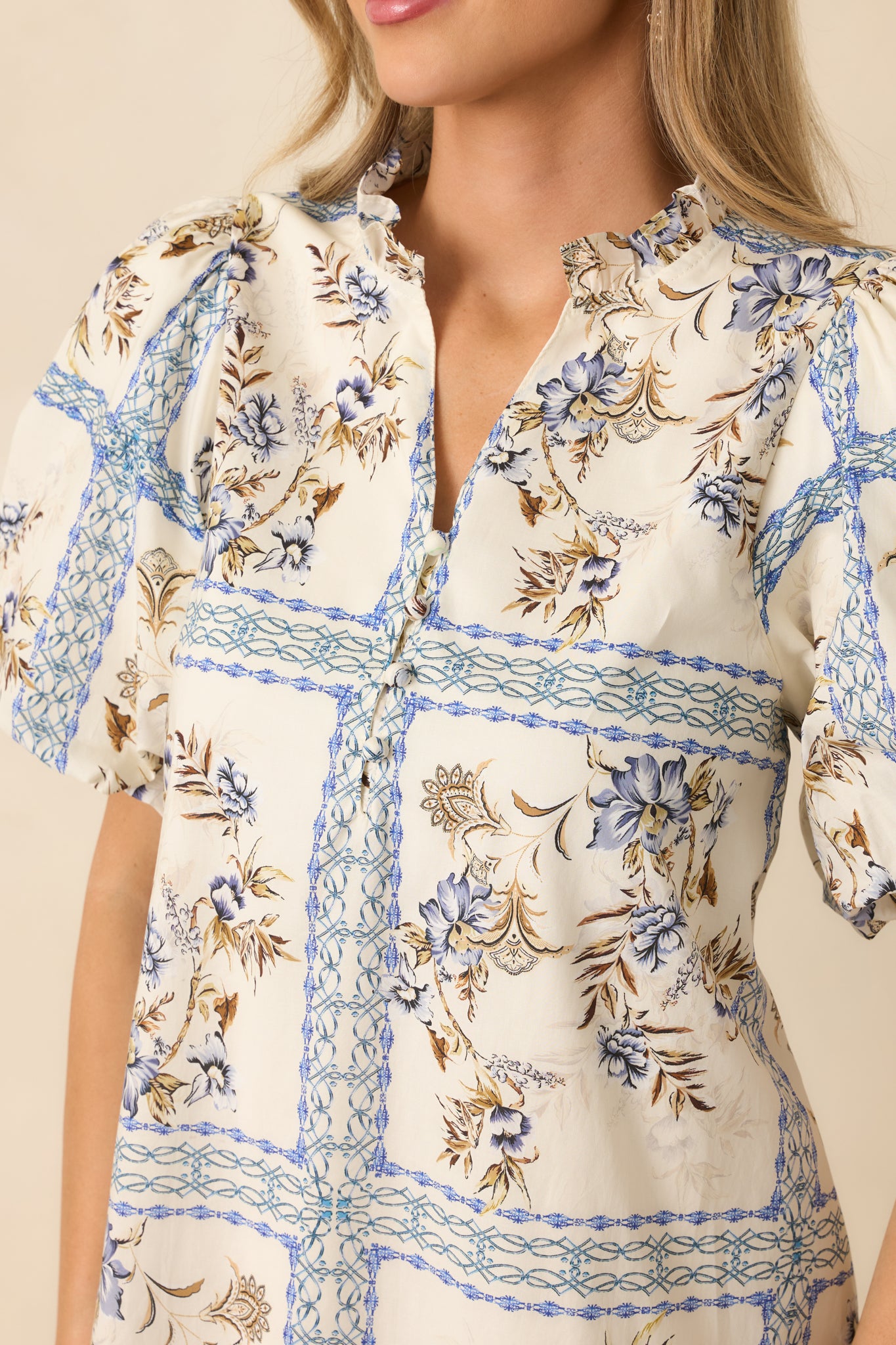 Tight detail of the neckline ruffle and printed cotton texture in a tile-inspired floral.