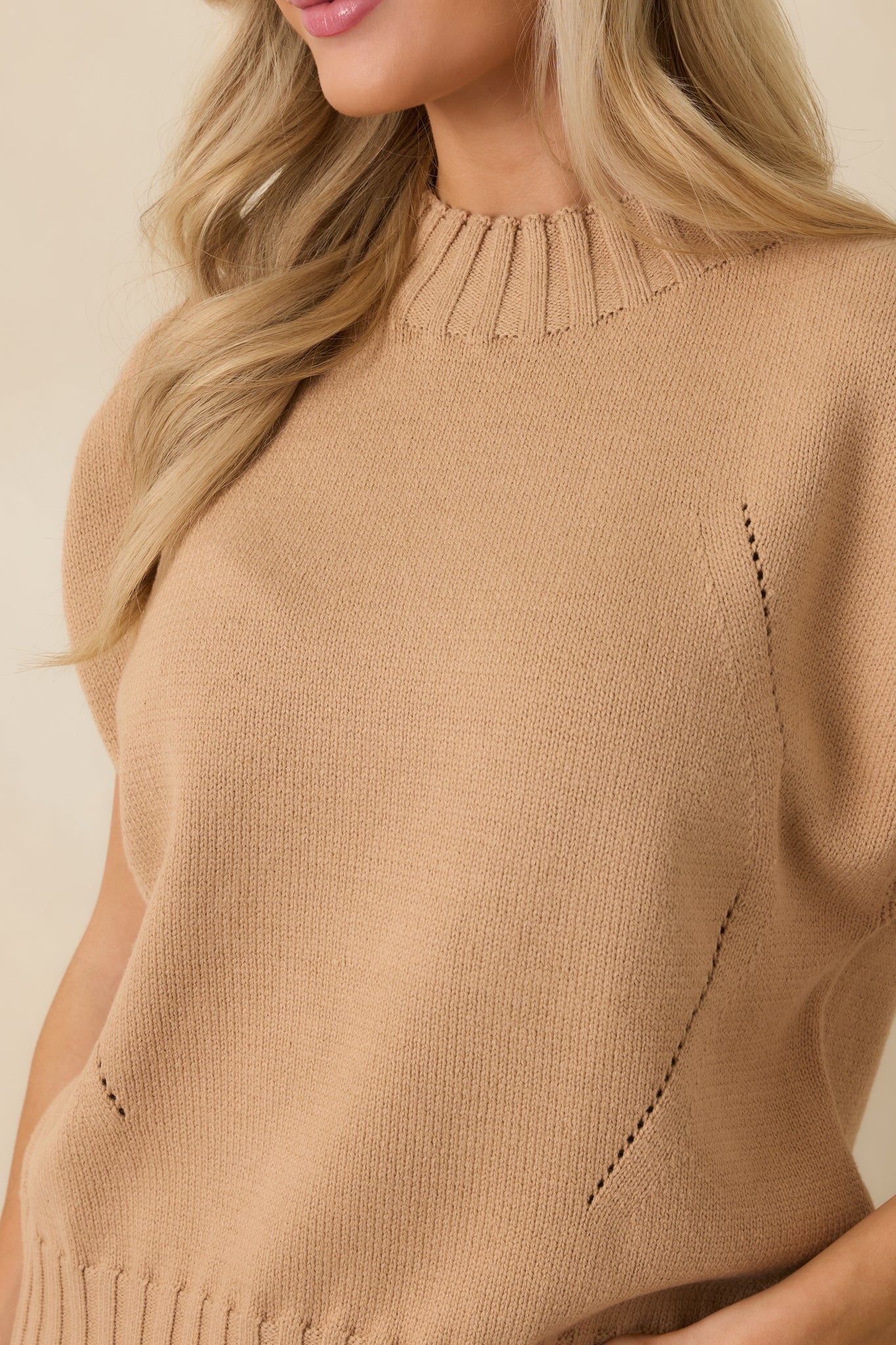 Detailed close-up of the tan sweater showcasing the ribbed neckline and fine knit texture.