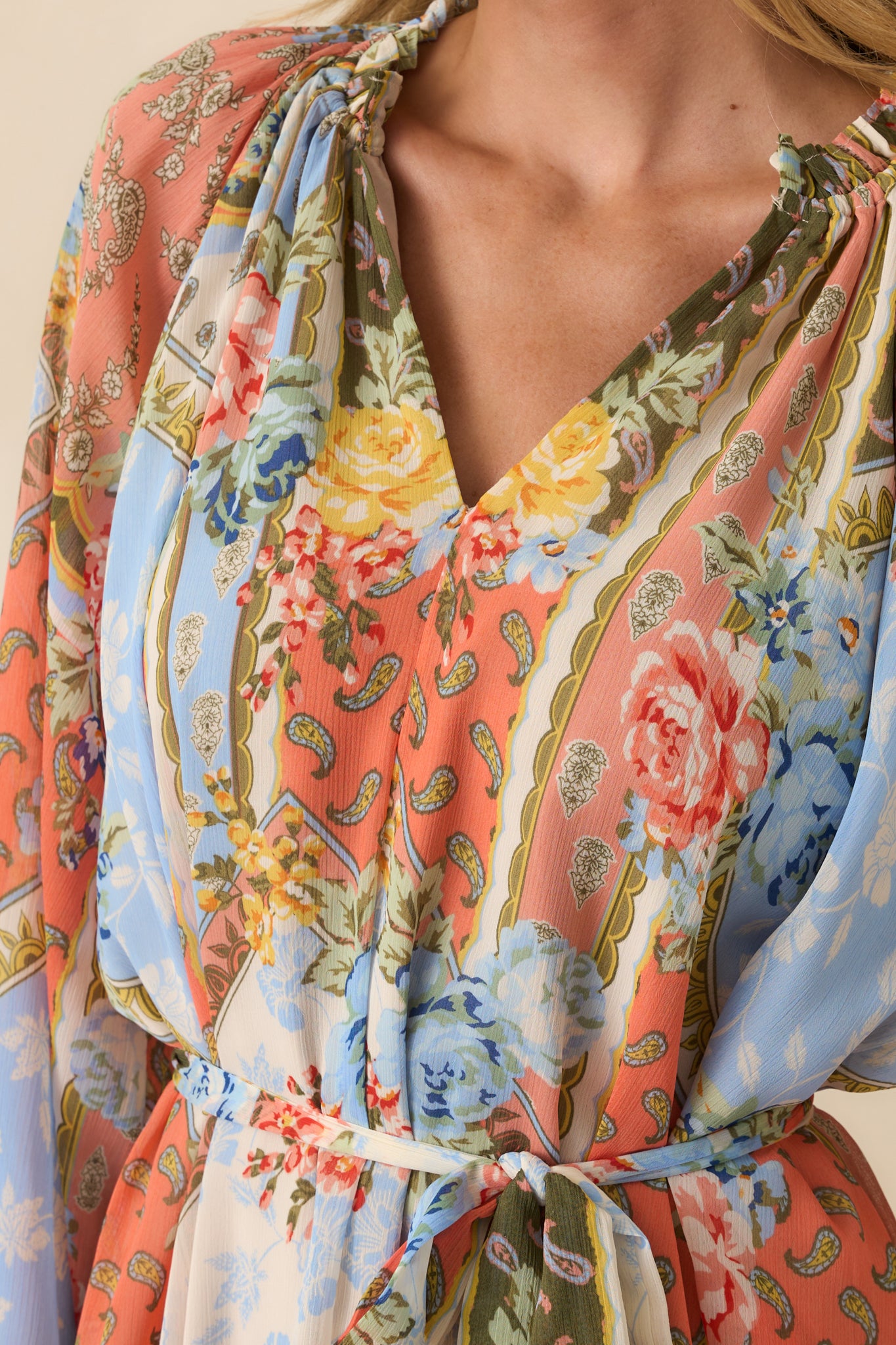 Close-up detail of the ruffled collar, self-tie belt, and elastic cuff on the floral print dress.