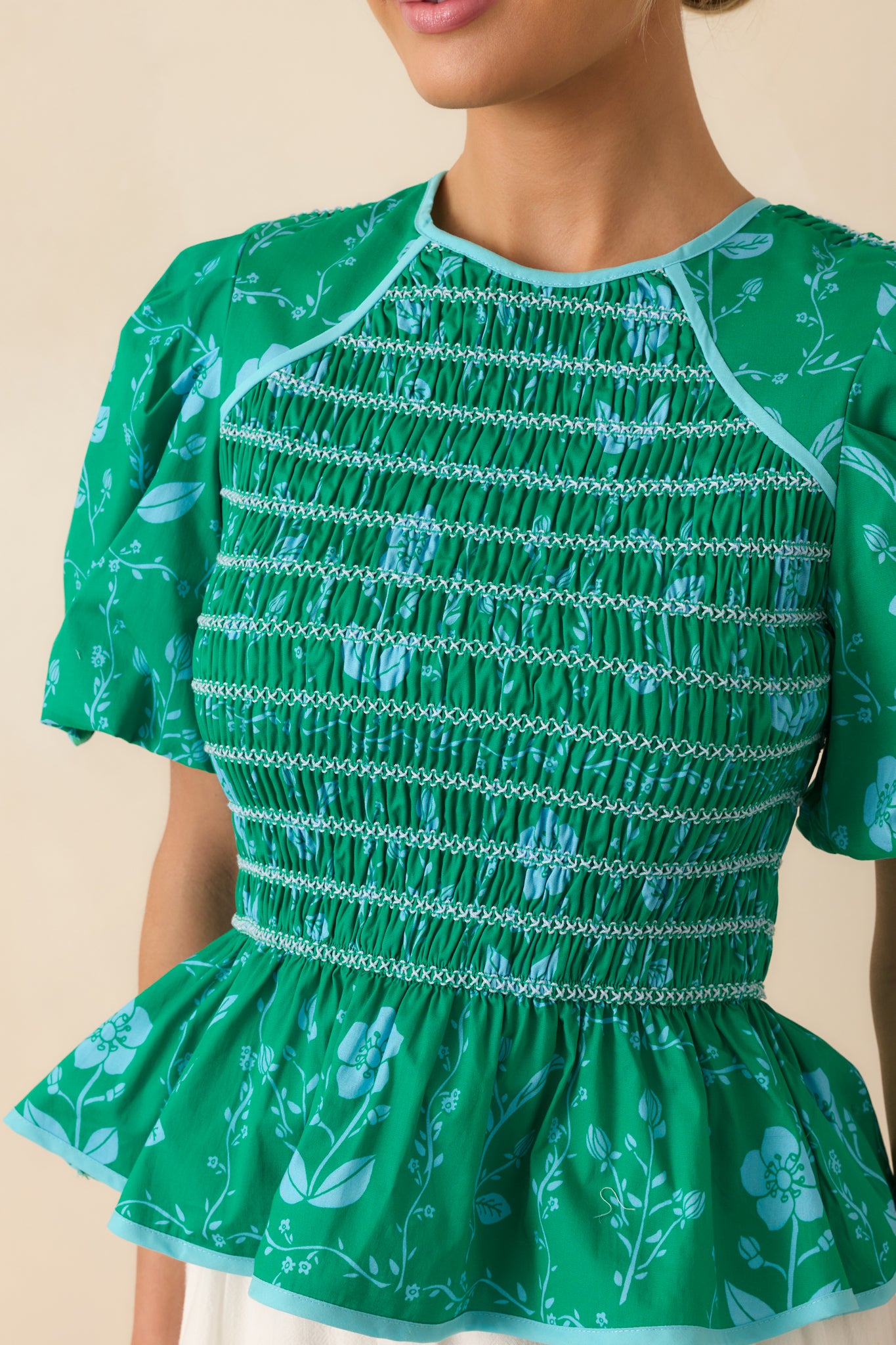 Close-up detail of the back keyhole button closure and upper fabric texture, including trim and floral print.