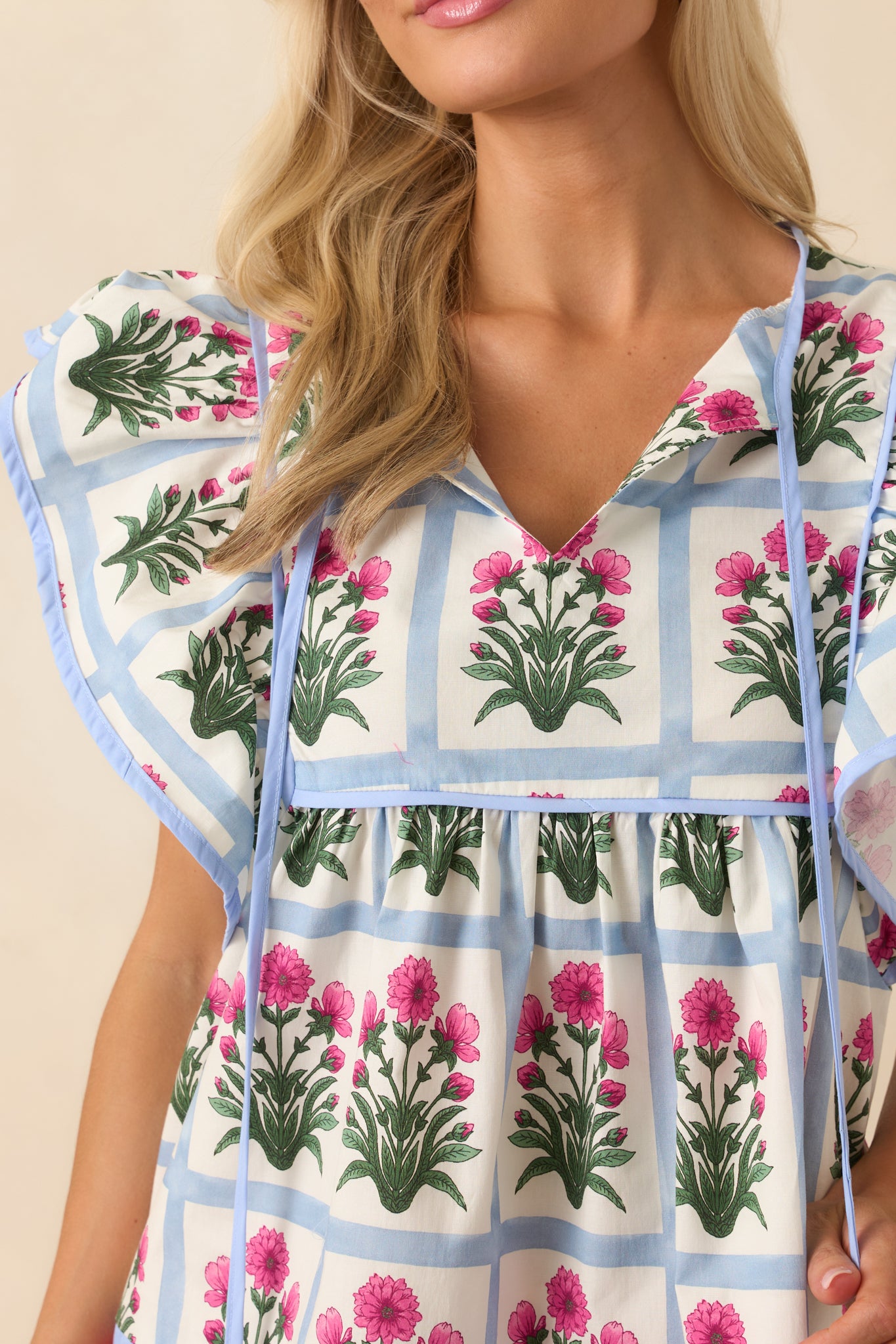 Detail photo of the fabric showcasing the fine geometric print, floral motif, and light blue trim stitching.