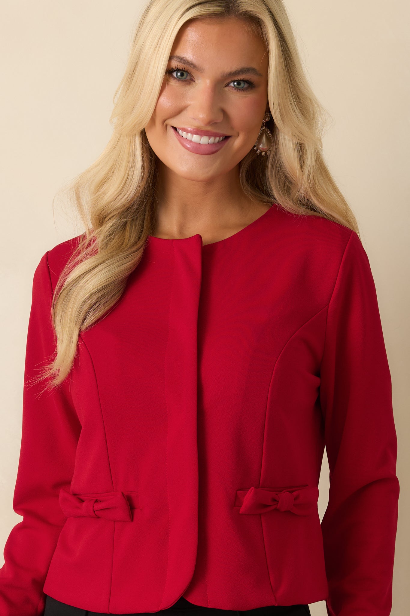 Detail-focused shot of the jacket’s cropped fit and bow-accented faux pockets, showcasing its elegant woven finish.