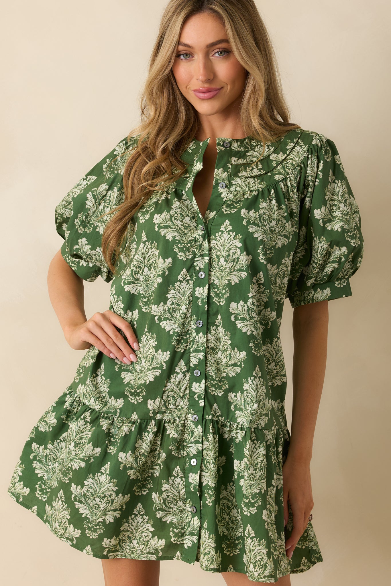 Cropped detail showing the button closure and structured collar of the green and ivory mini dress.