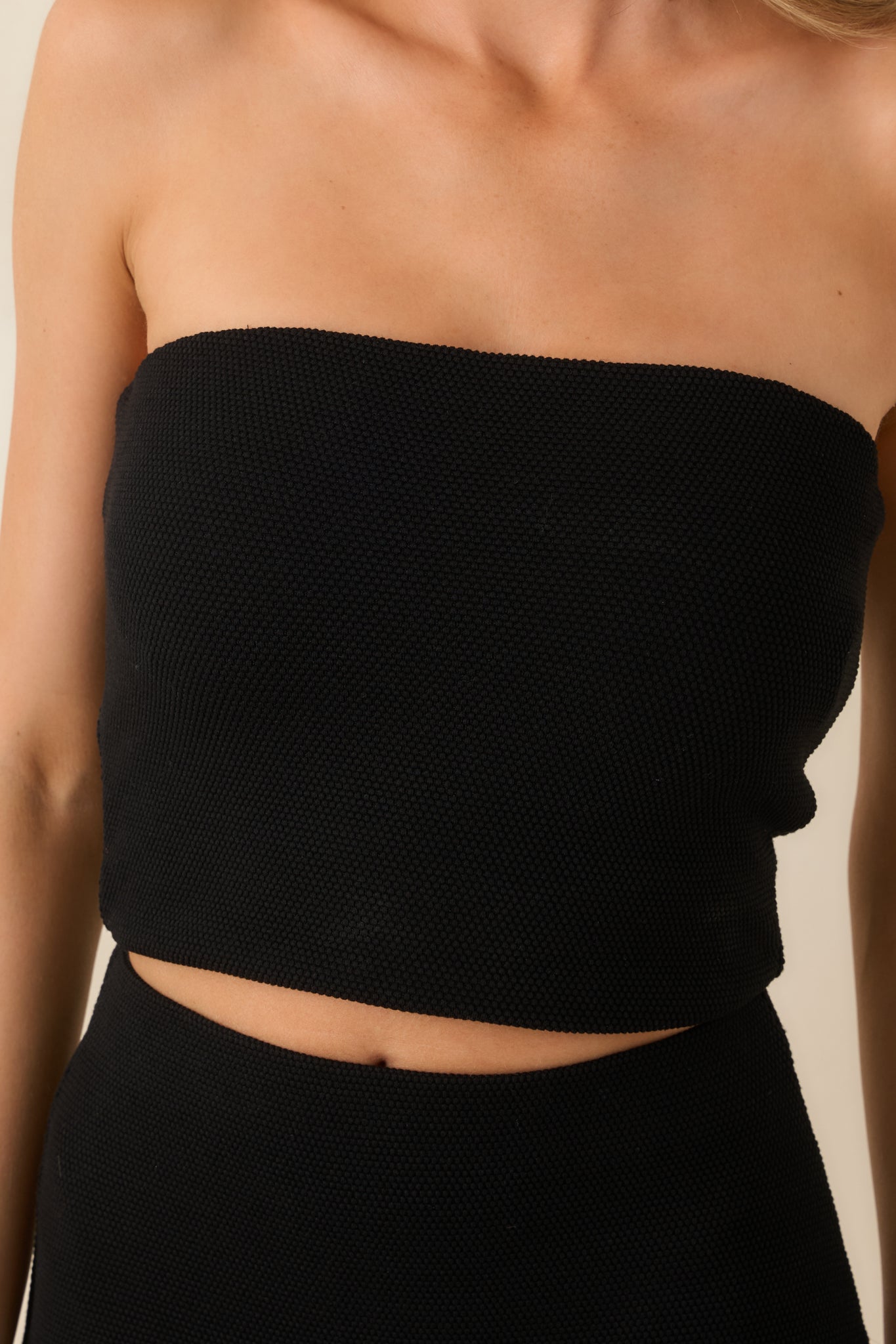 Detailed close-up of black tube top highlighting textured knit fabric and refined construction.