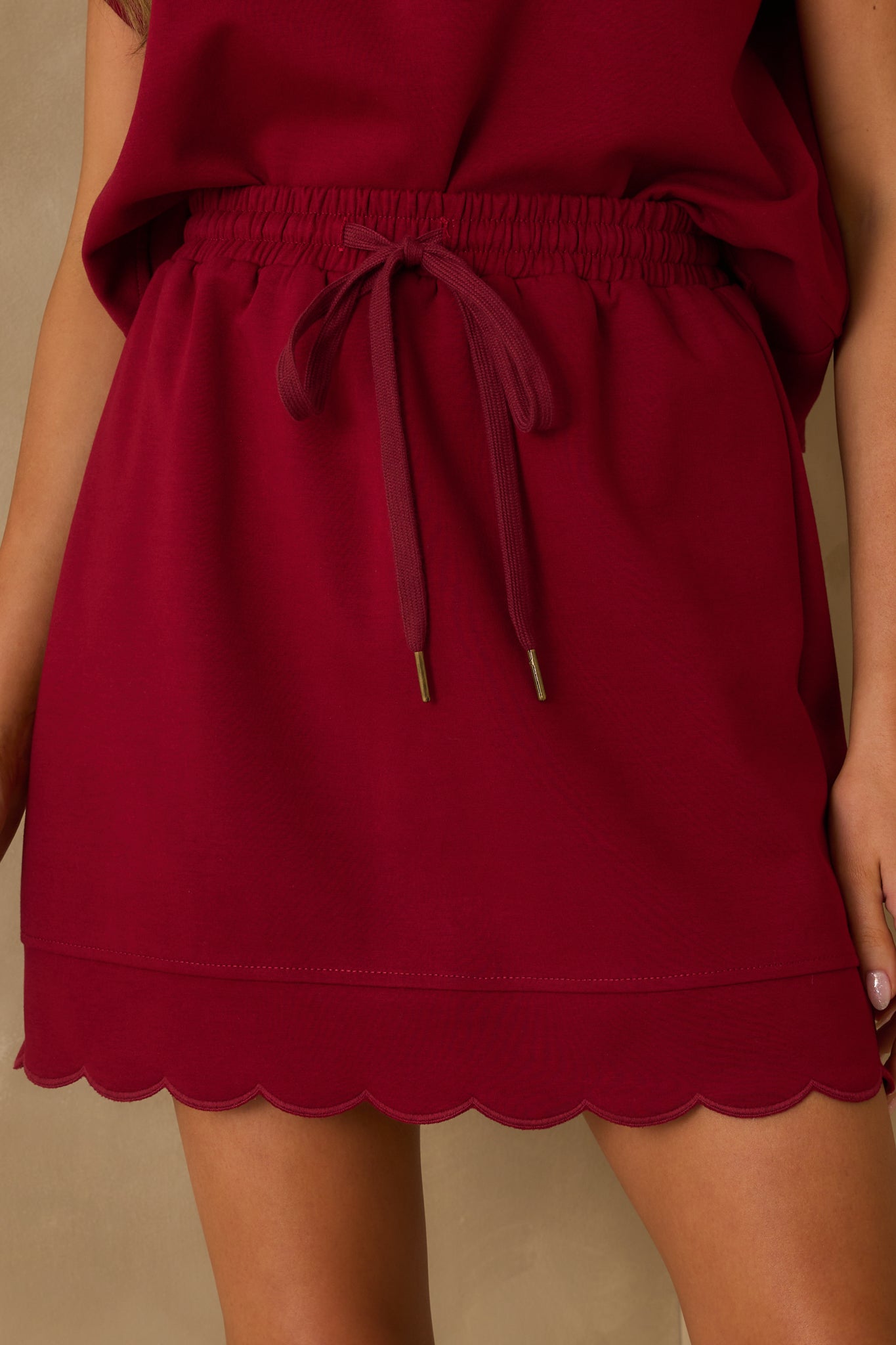 Detailed close-up of the burgundy skirt’s drawstring self-tie and elastic waistband stitching.