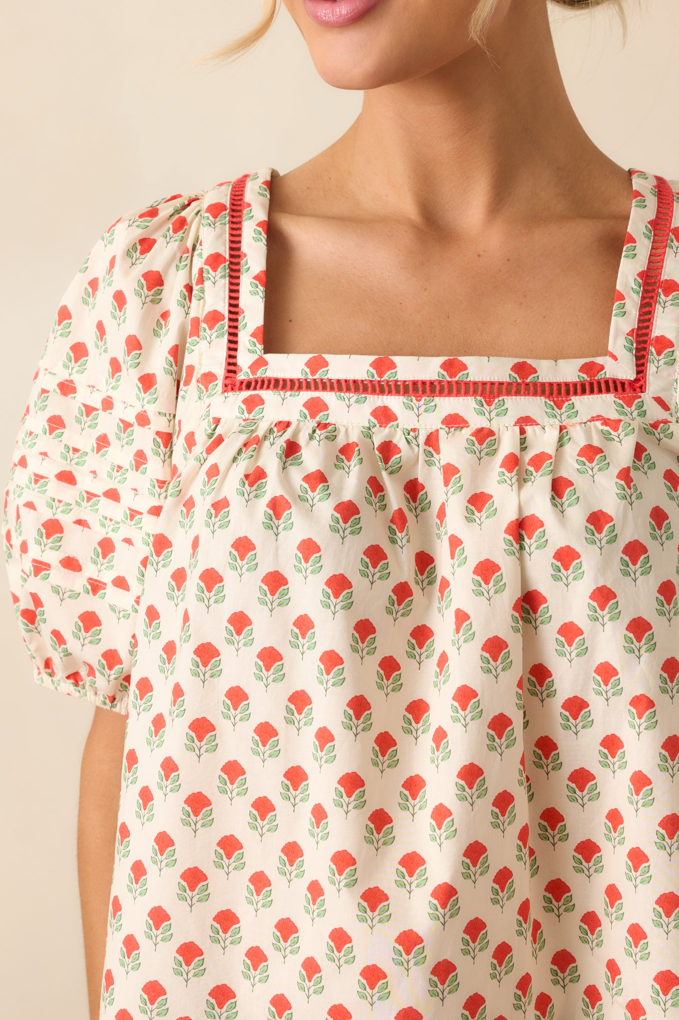 A detailed image capturing the intricate ladder lace trim and vibrant red floral pattern on the soft cotton top.
