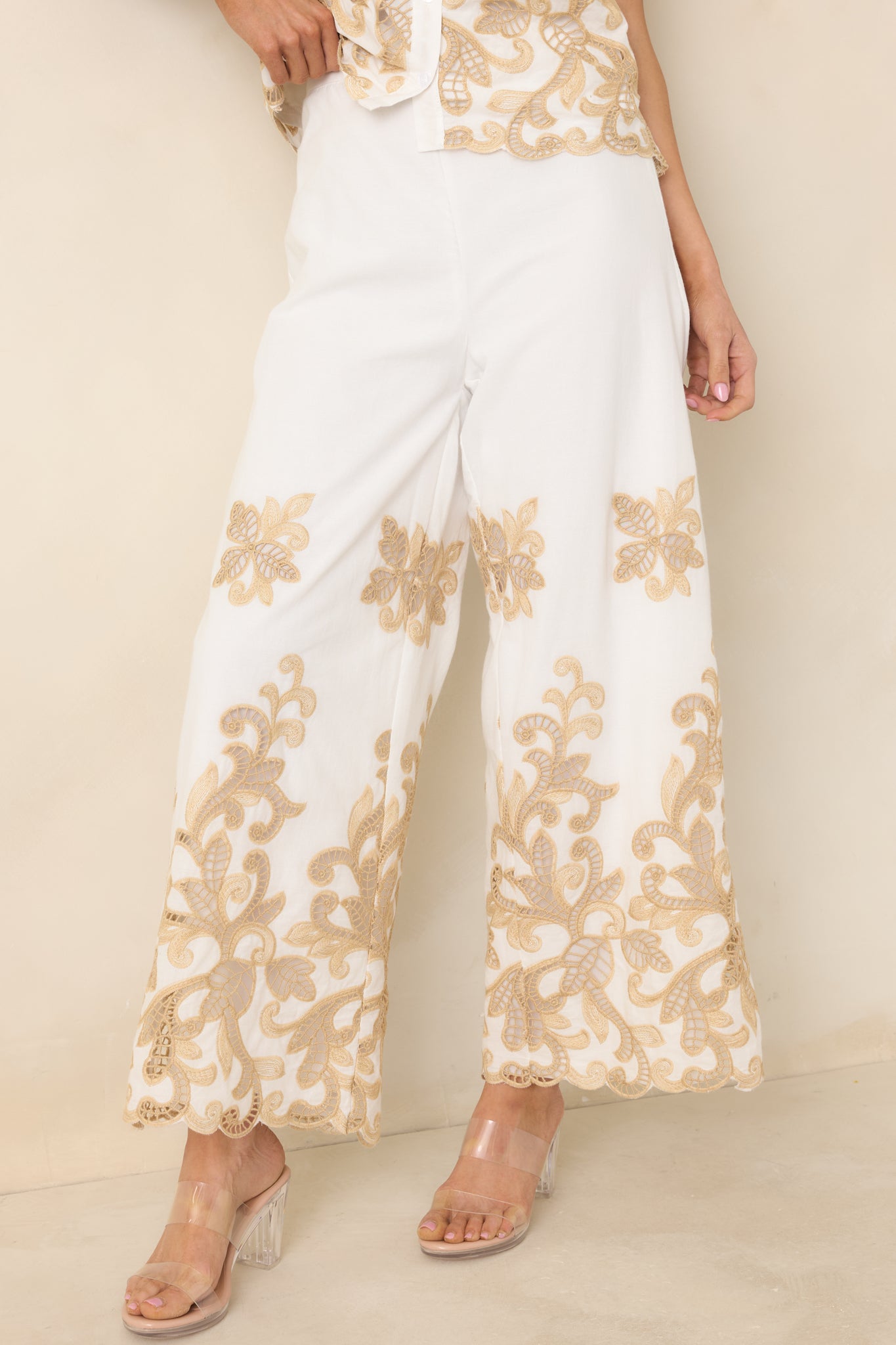 Detailed look at lace appliqué along ivory wide leg silhouette.