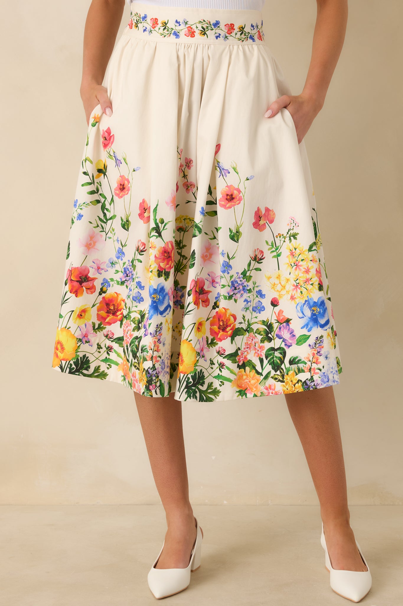 Detailed look at the floral border print at the hem of the white midi skirt.