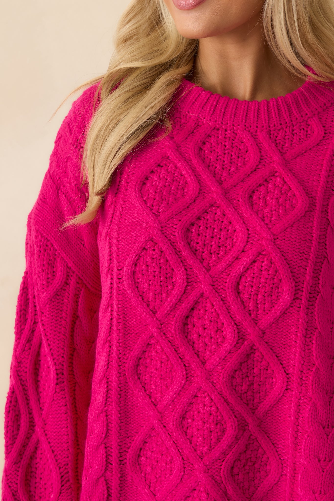 Detailed look at the cable knit pattern and textured knit fabric of the sweater.
