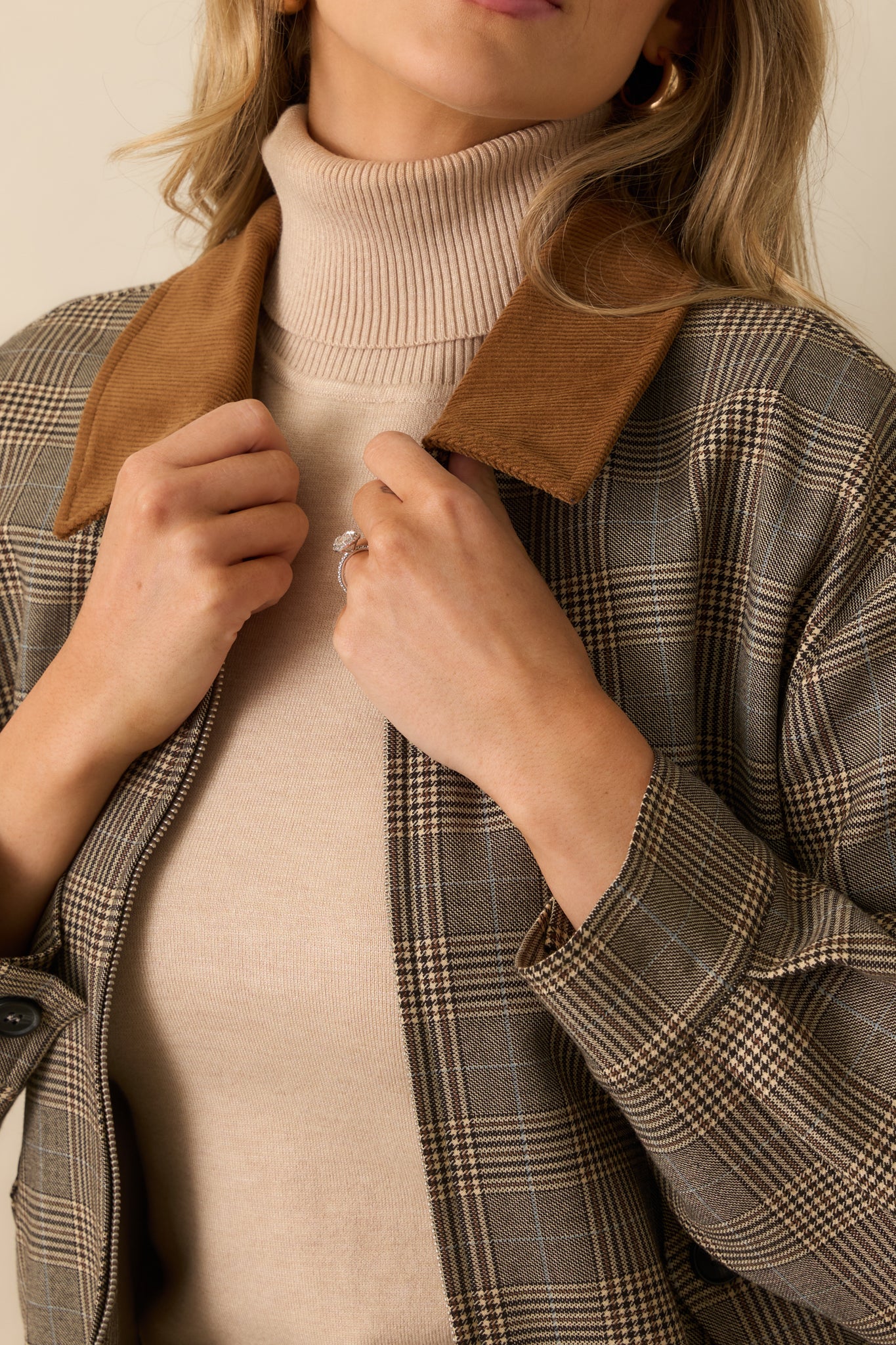 Detailed look at the multi plaid woven fabric, corduroy collar, and front button flap pocket of the brown bomber jacket.