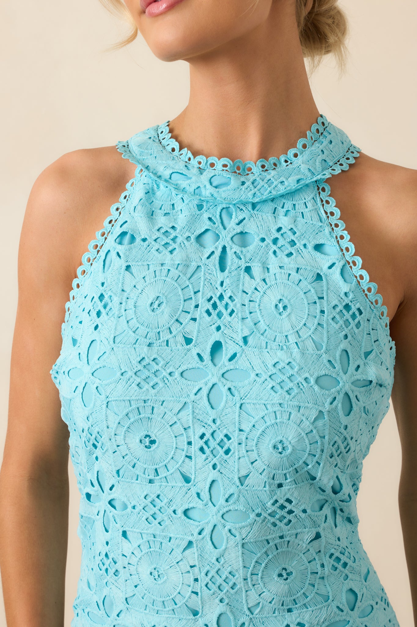 Detailed shot of the embroidered floral pattern and eyelet design on the halter neckline and upper bodice.