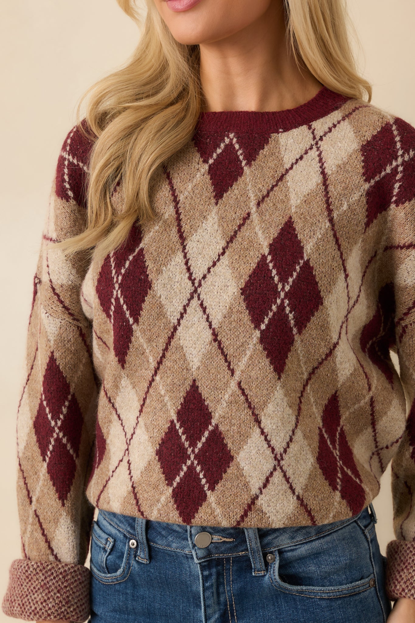 Detailed view of the argyle knit pattern and ribbed trim on the sweater.