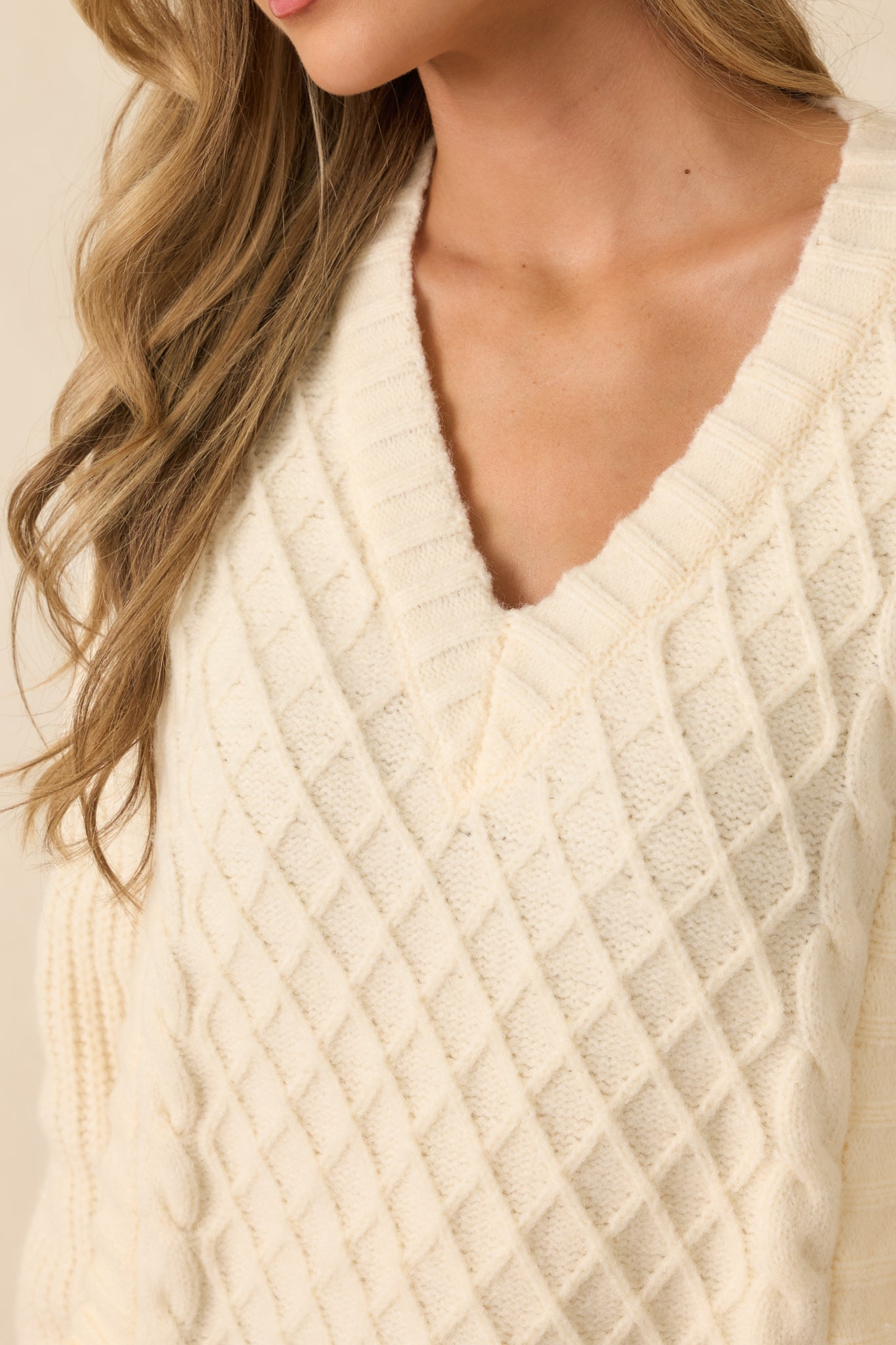 Detailed view of ivory knit texture with dimensional stitching and soft yarn fibers.