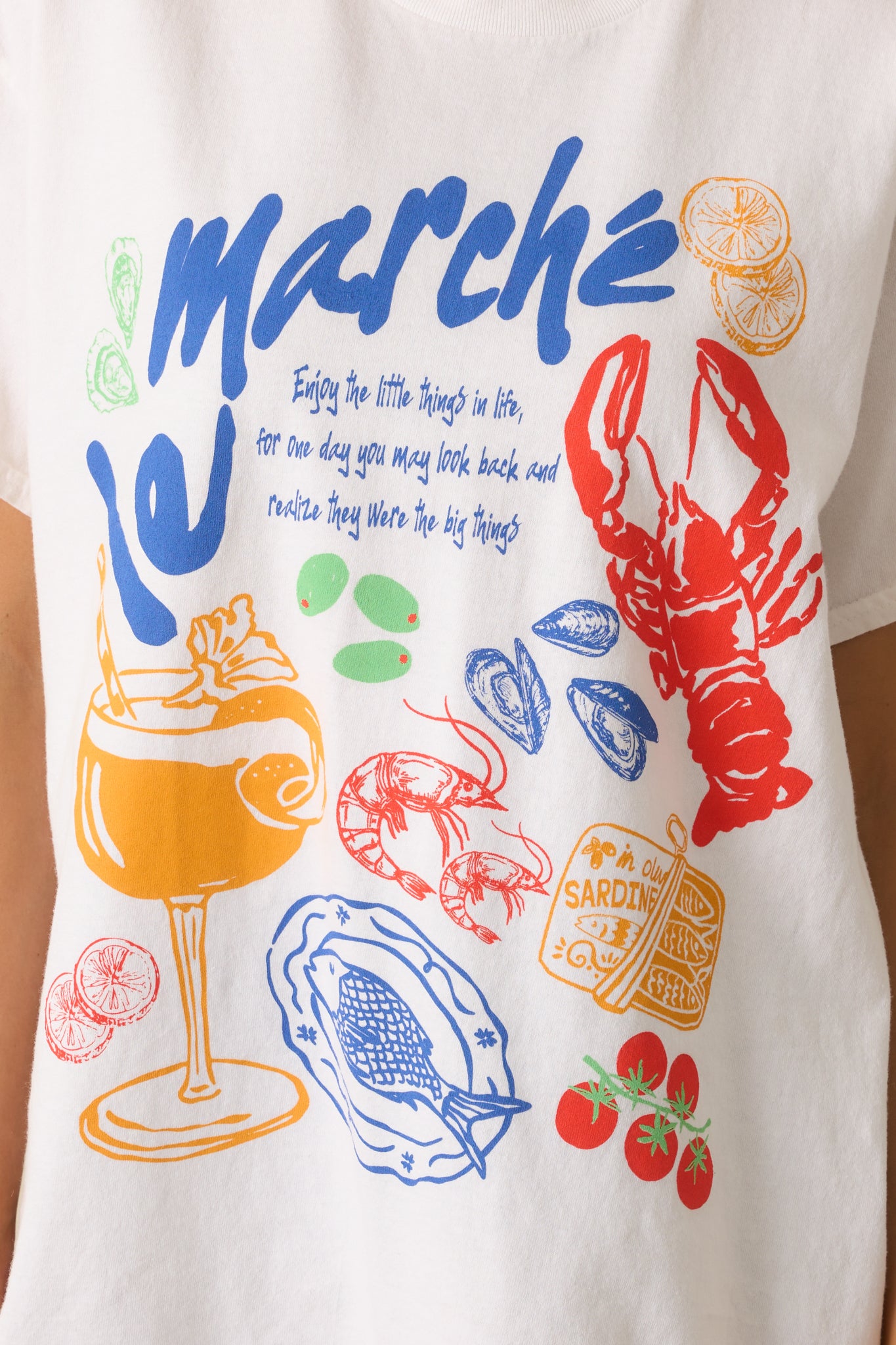 Detailed view of the colorful coastal Europe-inspired graphic and soft cotton texture of the white tee.