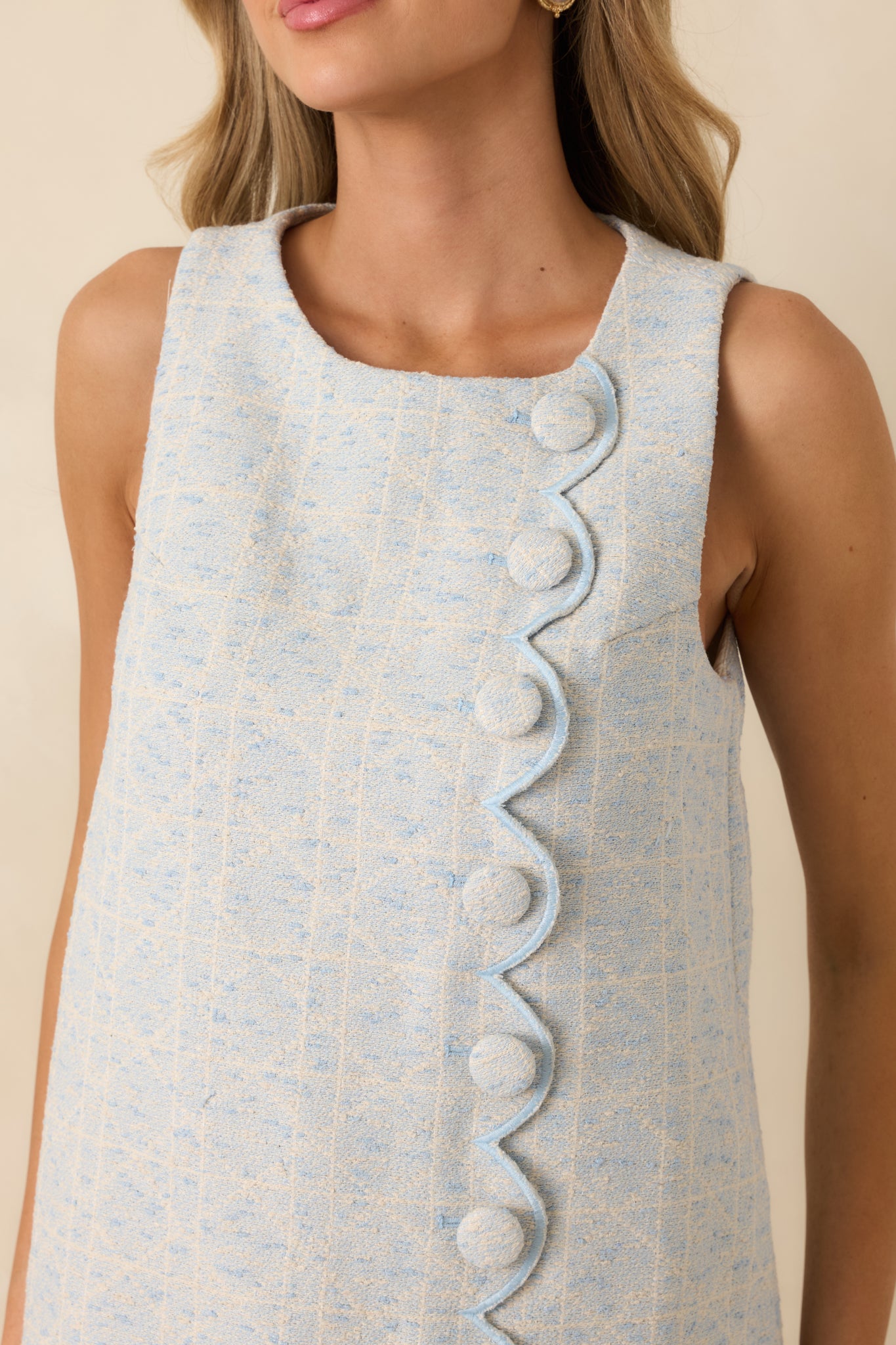 Detailed view of light blue textured woven fabric and one fabric-covered decorative button.