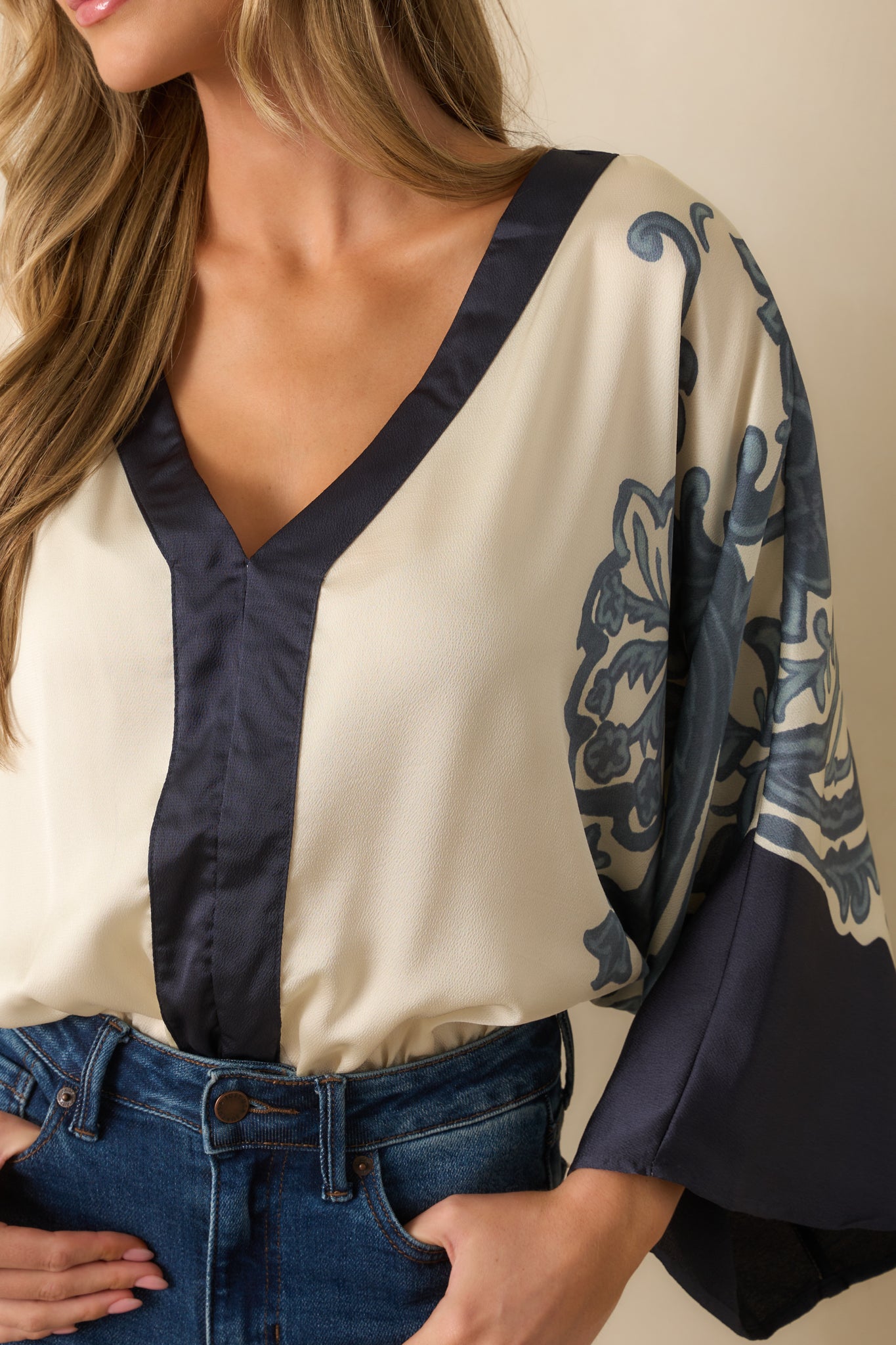 Detailed view of the bodysuit fabric, showing the ivory background, navy baroque-inspired print, and contrast trim.