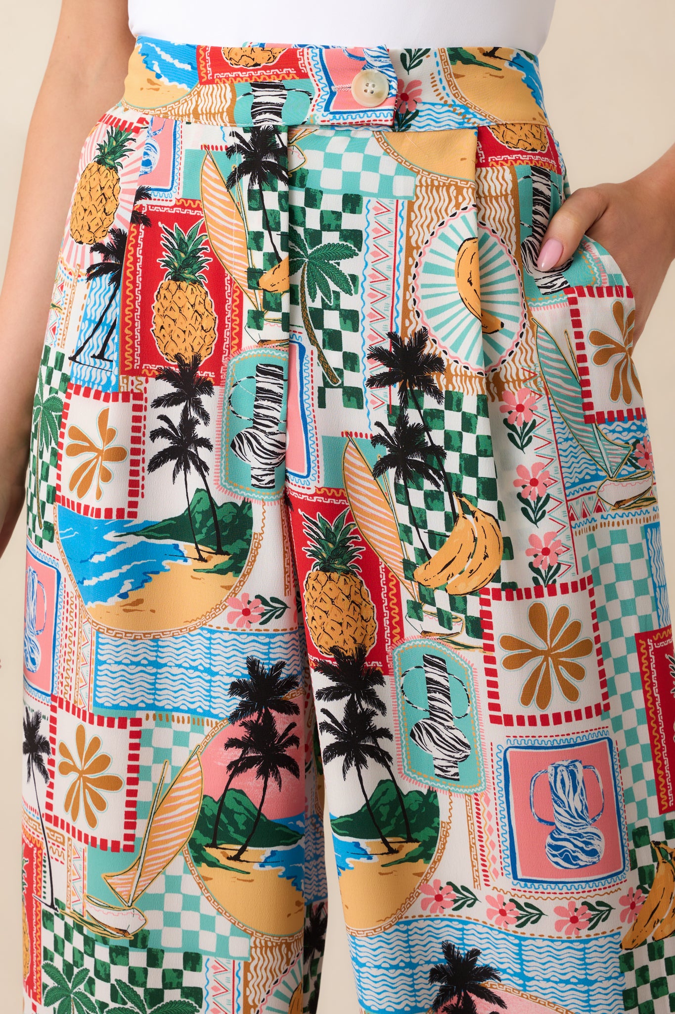 Detail close-up of tropical pants showing the beige button, zipper fly, and stitching around the waistband.