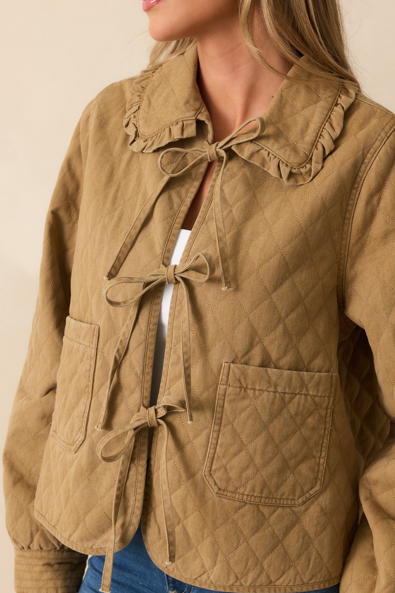 Diamond quilted fabric and ruffle-trim collar detail on the khaki brown jacket.