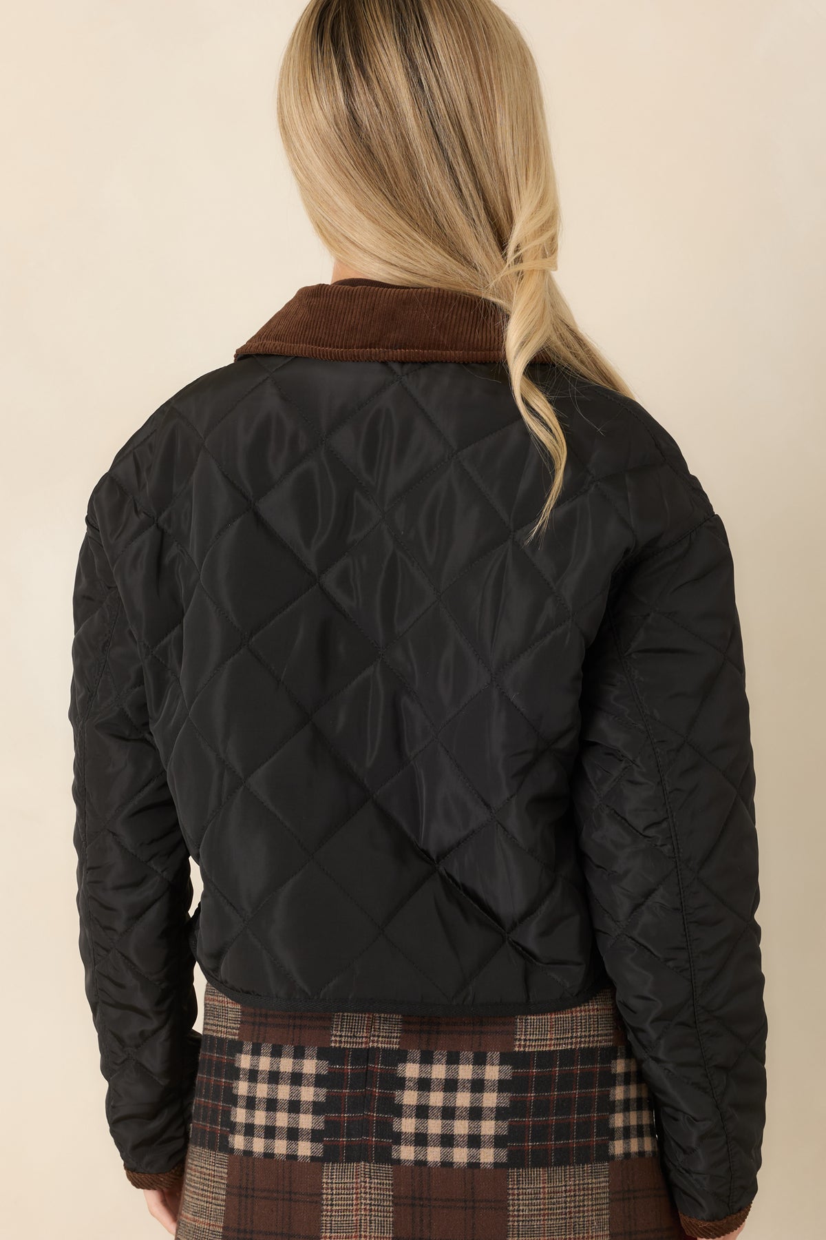 Diamond-quilted jacket back with long sleeves, a slightly cropped hem, and black binding along the bottom edge.