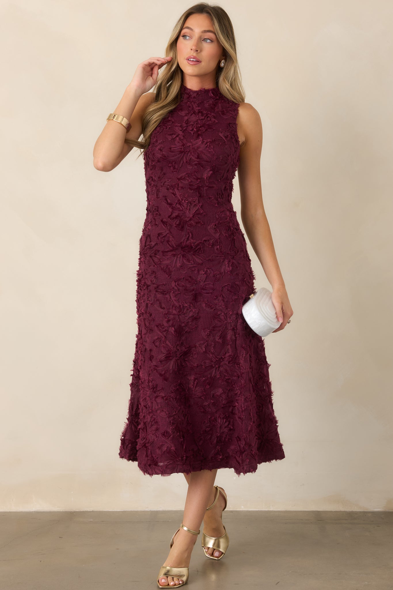 Statement knit dress showcasing dimensional floral appliqué throughout the fabric, a streamlined sleeveless bodice, and graceful midi-length skirt.
