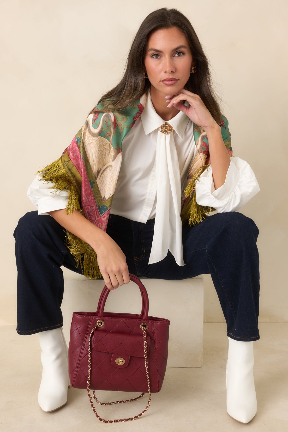 Blouse with draped neck ties, gathered shoulders, and a relaxed silhouette accented by a sculptural gold-tone detail.