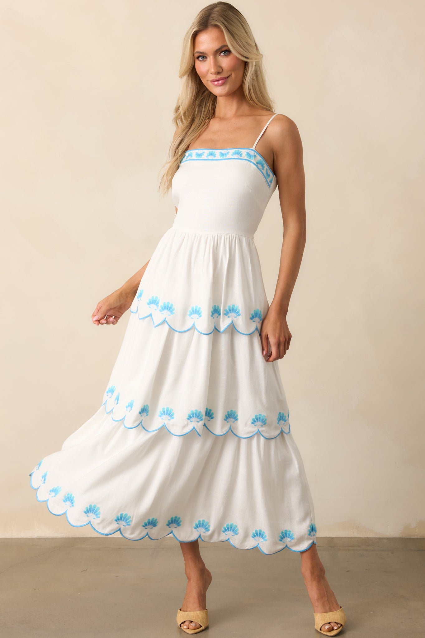 Complete front view of the dress emphasizing the flowing silhouette and contrast of blue embroidery on white fabric.