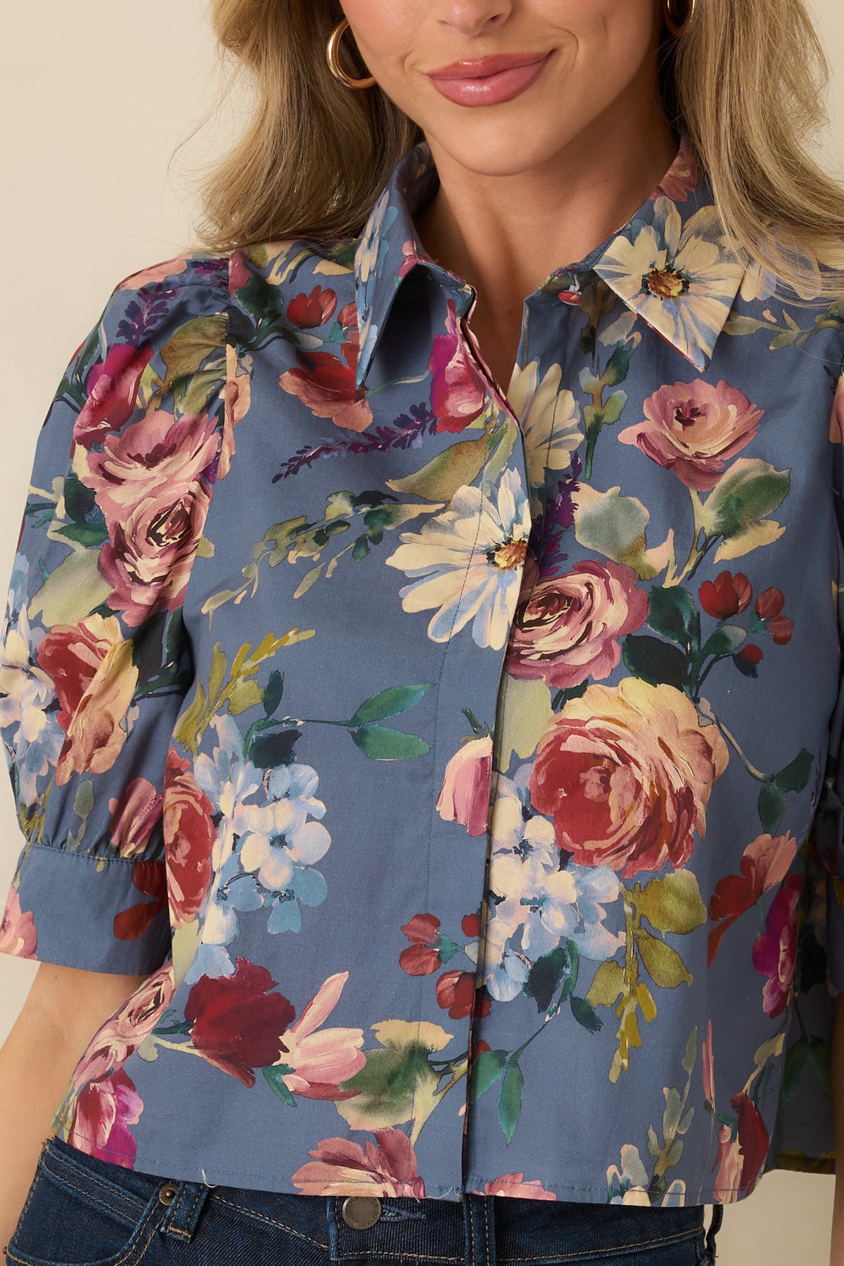 Close-up of the dusty blue blouse showing painterly roses, daisies, hydrangeas, and the pointed collar.