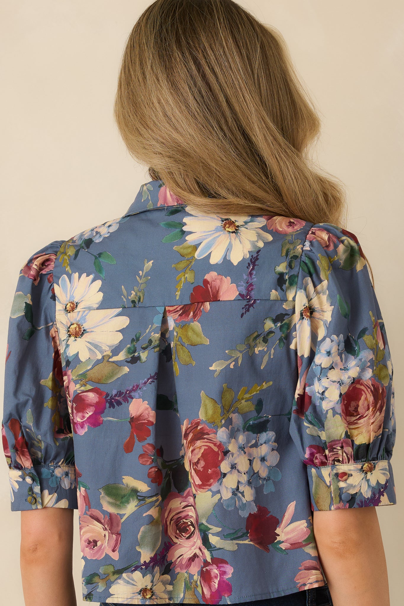 Rear view of the dusty blue floral blouse showing the relaxed silhouette and back box pleat.