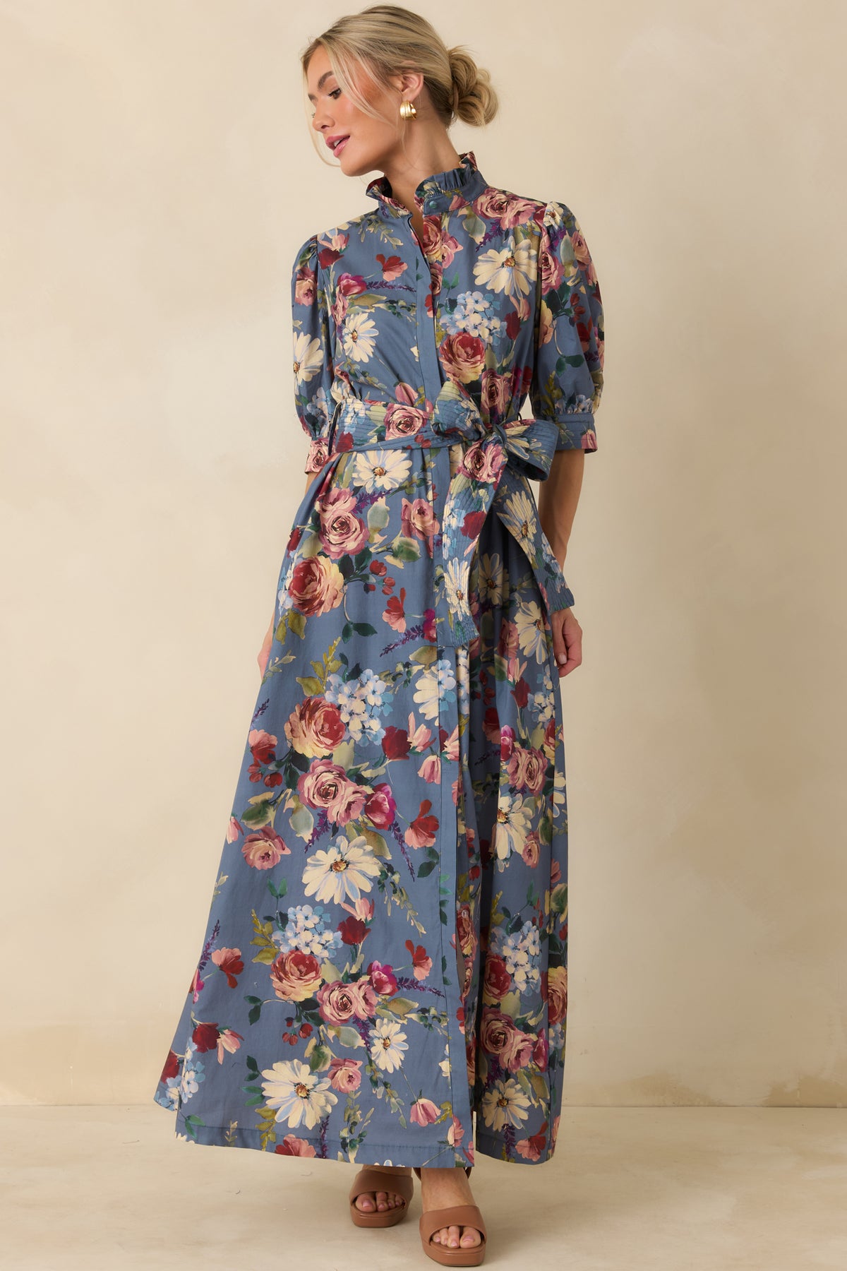 Dusty blue floral maxi dress featuring a sweeping skirt, ruffled stand collar, and coordinating waist tie.
