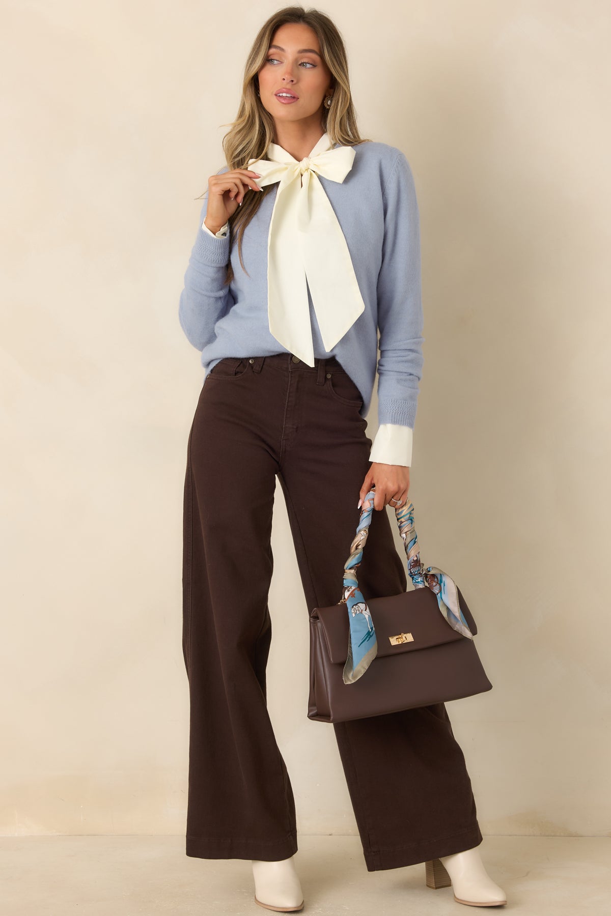 Dusty blue knit top with a V-neckline, long sleeves, and ribbed trim along the hem.