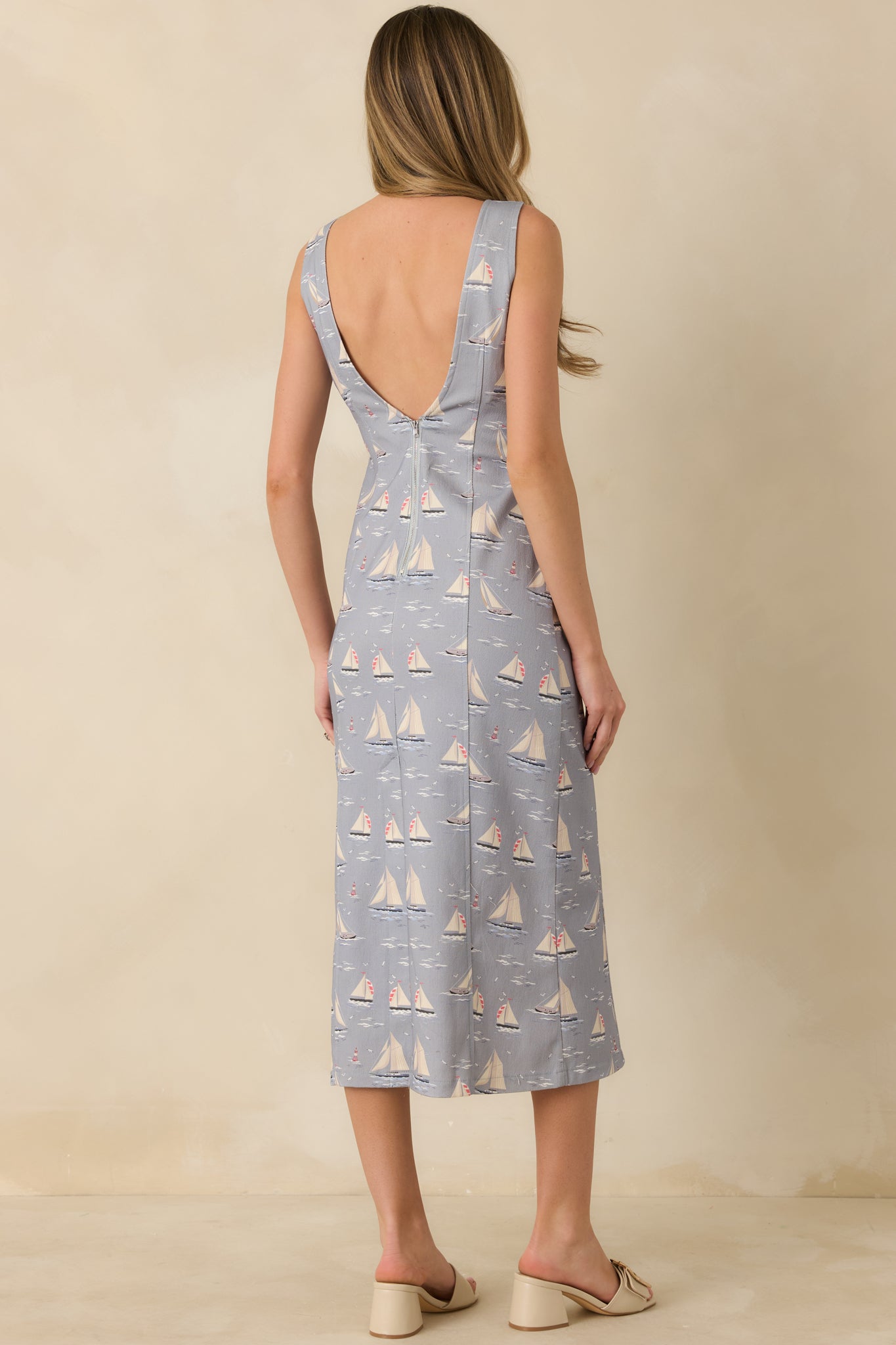 Dusty blue sleeveless midi dress displaying the straight silhouette from the rear with allover sailboat print and lightweight knit finish.