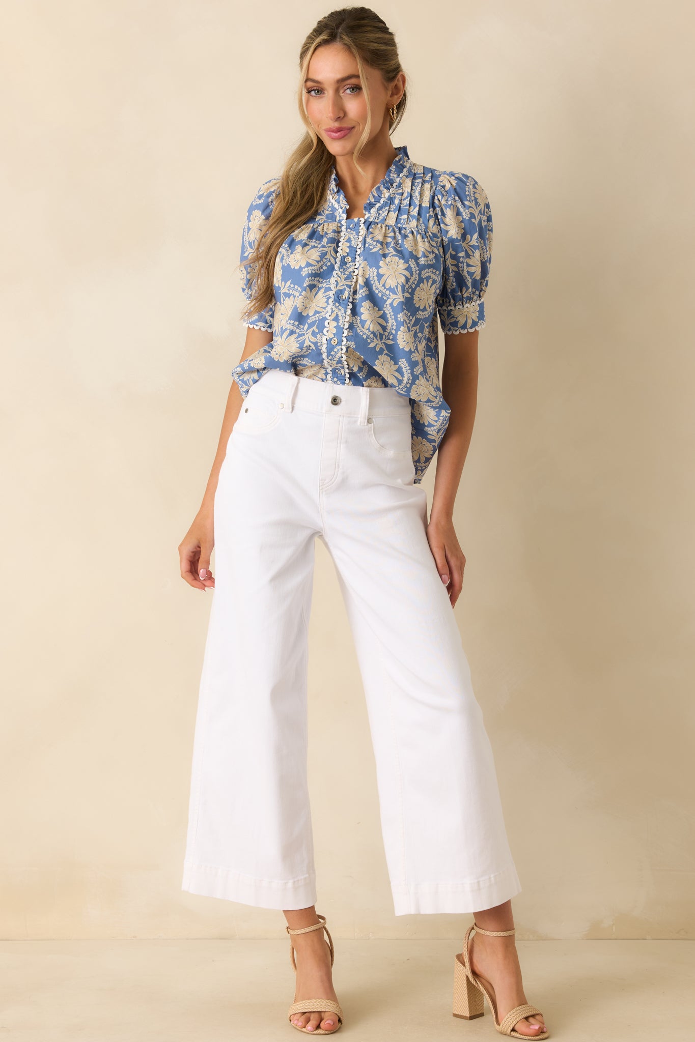 Dusty blue floral blouse featuring puff sleeves, a scalloped button placket, ruffled collar, and versatile relaxed shape.