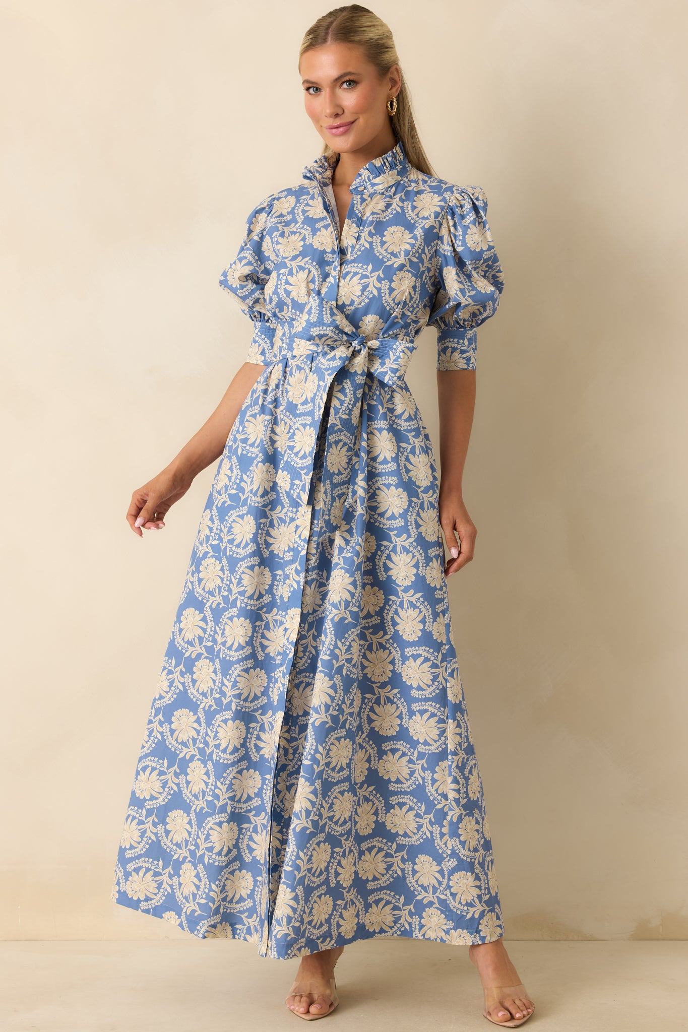 Dusty blue floral cotton maxi dress designed with puff sleeves, smocked cuffs, a flattering tied waist, and hidden side pockets.